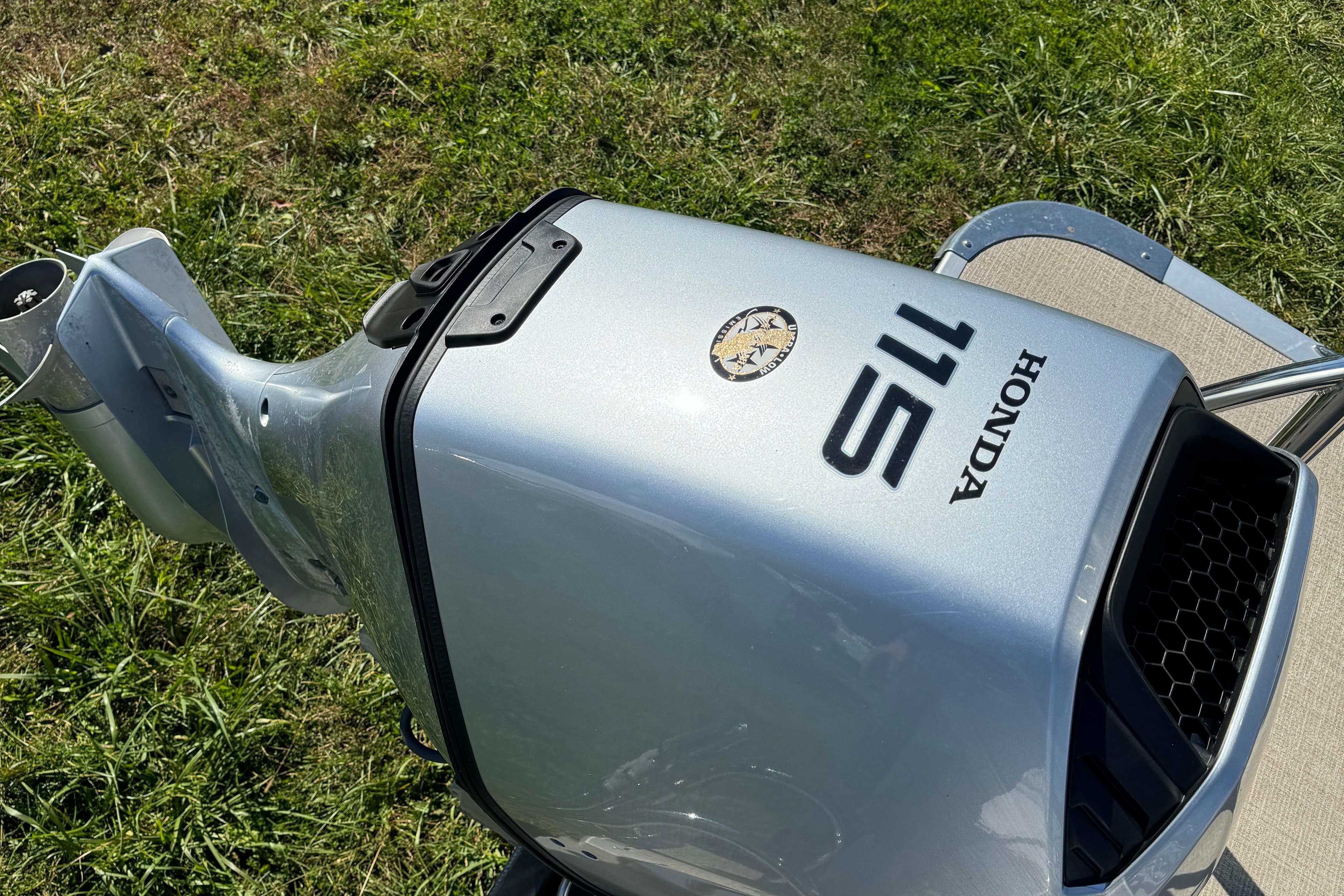 Honda 115 outboard motor on 2022 Avalon LSZ Quad Lounger 2385, grass background.