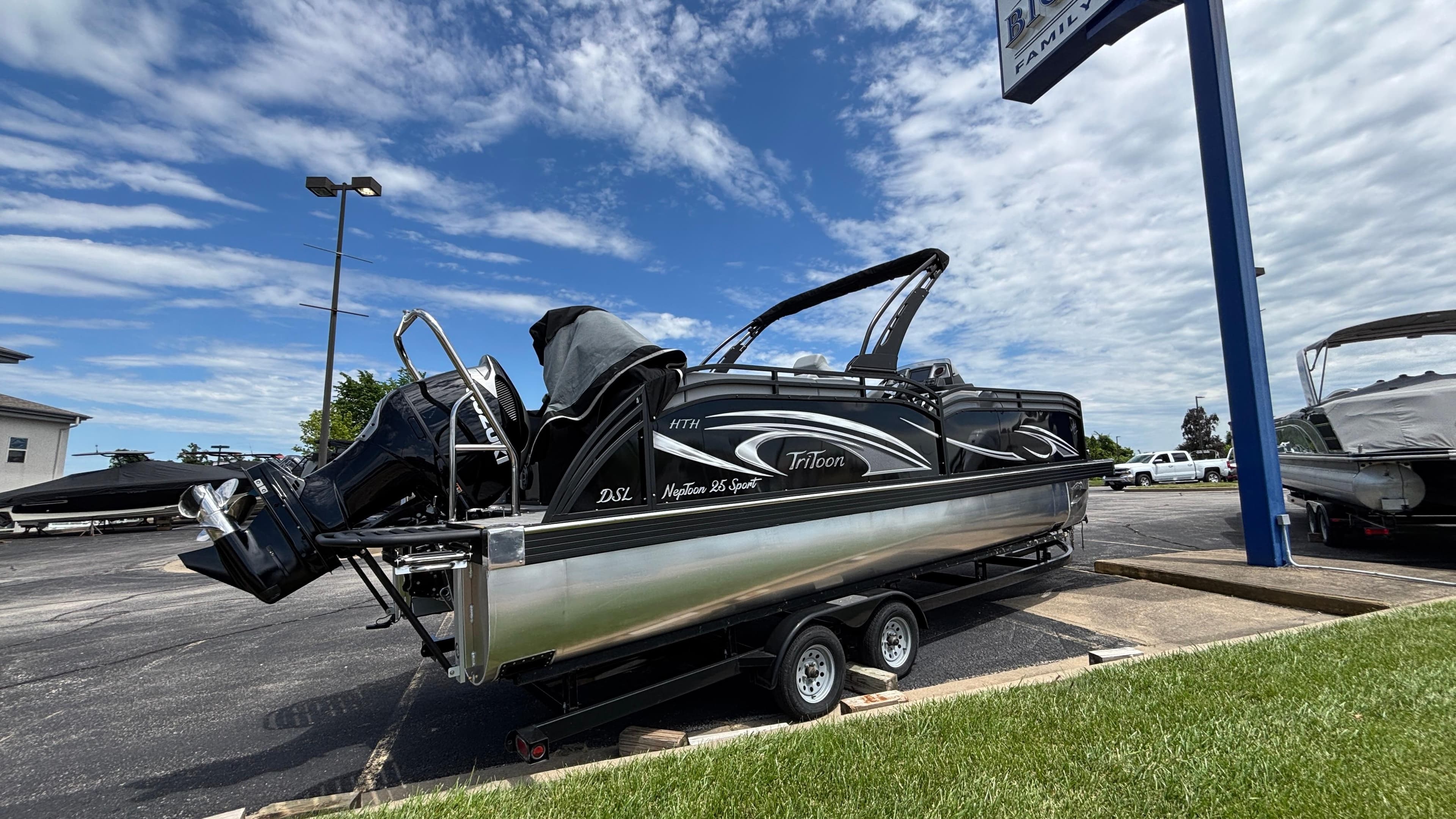 2025 JC Neptoon 25TT Sport pontoon boat on trailer under a partly cloudy sky.