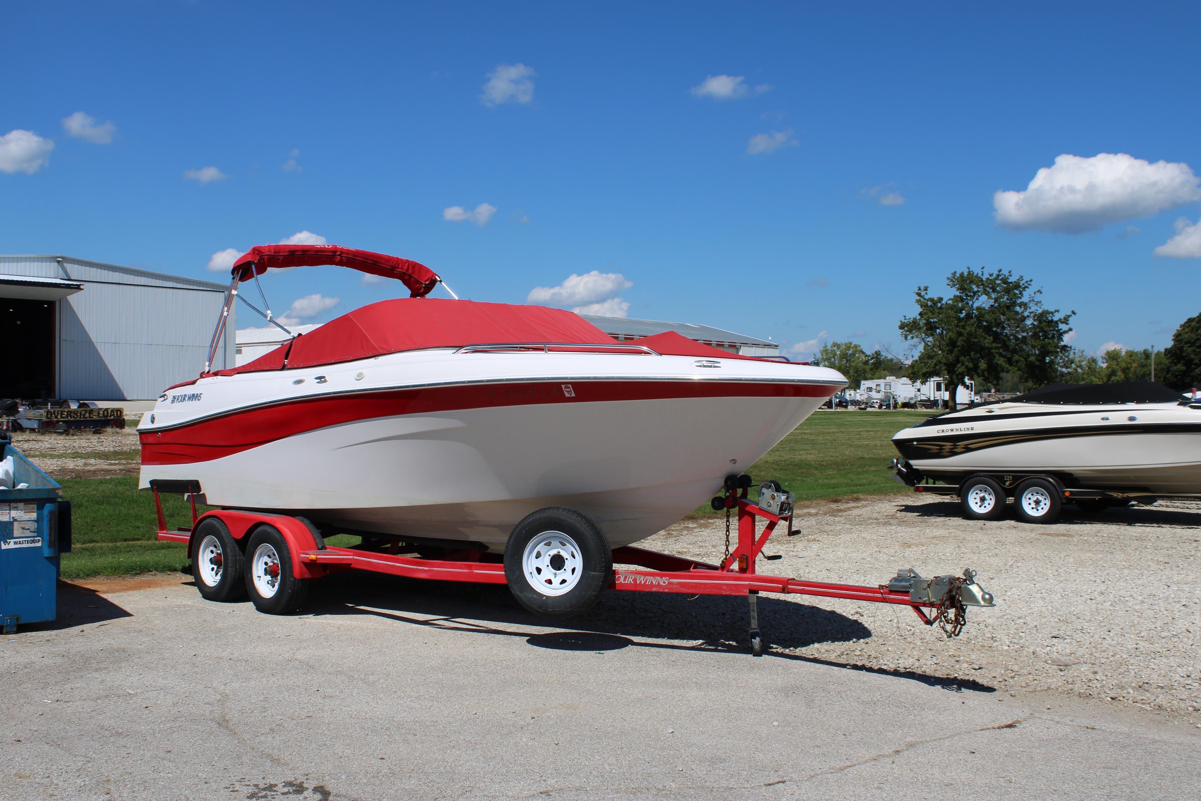 2002 Four Winns 240 Horizon boat on red trailer, parked outdoors under blue sky.