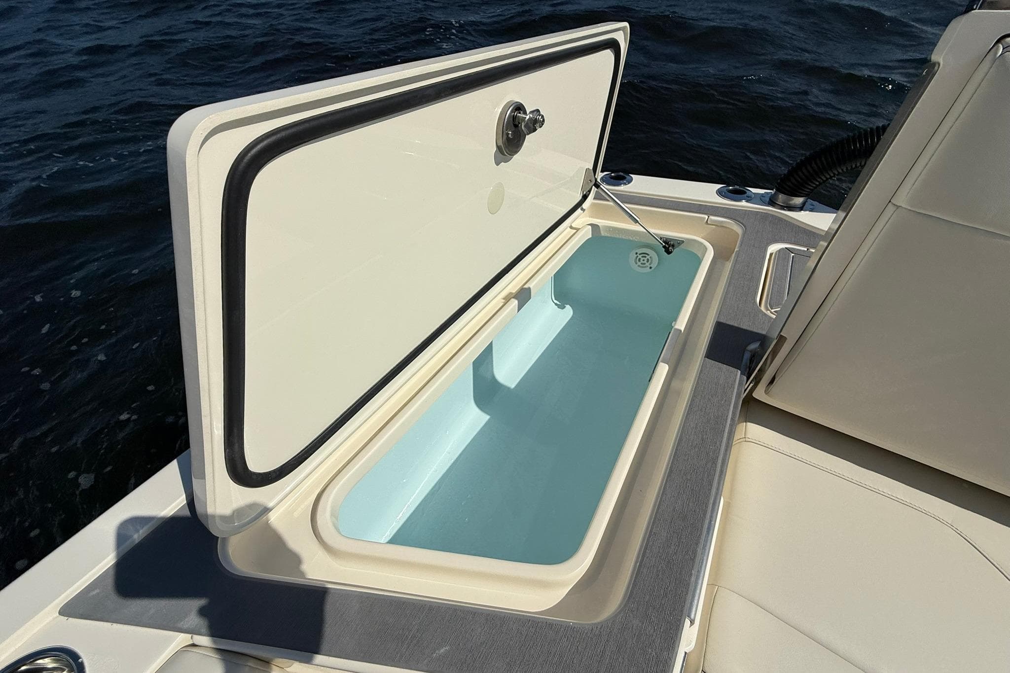 Open storage compartment on 2026 Scout 281 XSS boat, with ocean background.