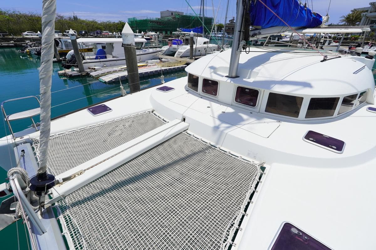 2013 Lagoon 380 catamaran docked at marina, featuring spacious deck and netting.