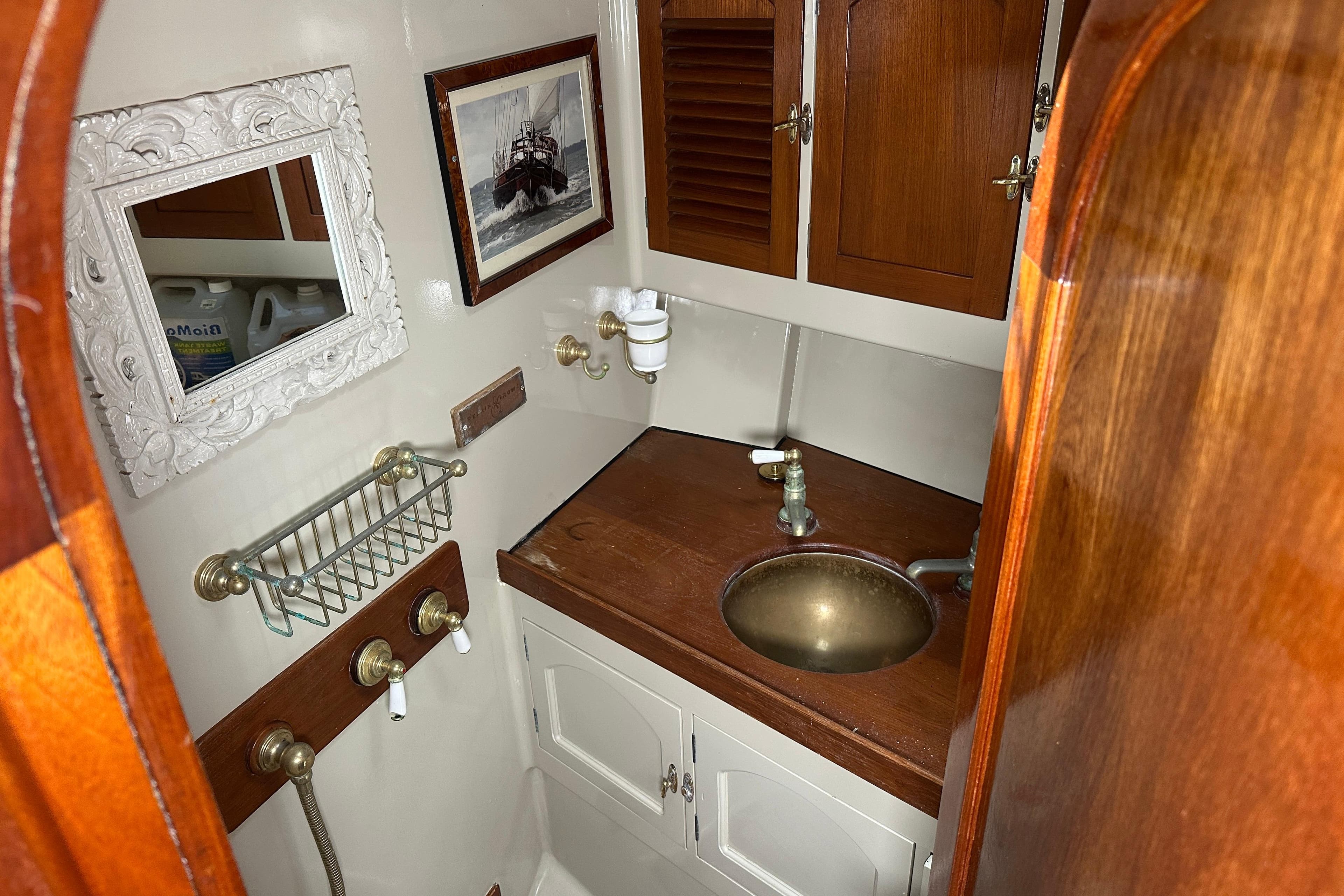 Custom 1995 Dennis Ganley boat bathroom with wooden cabinets and brass sink fixtures.