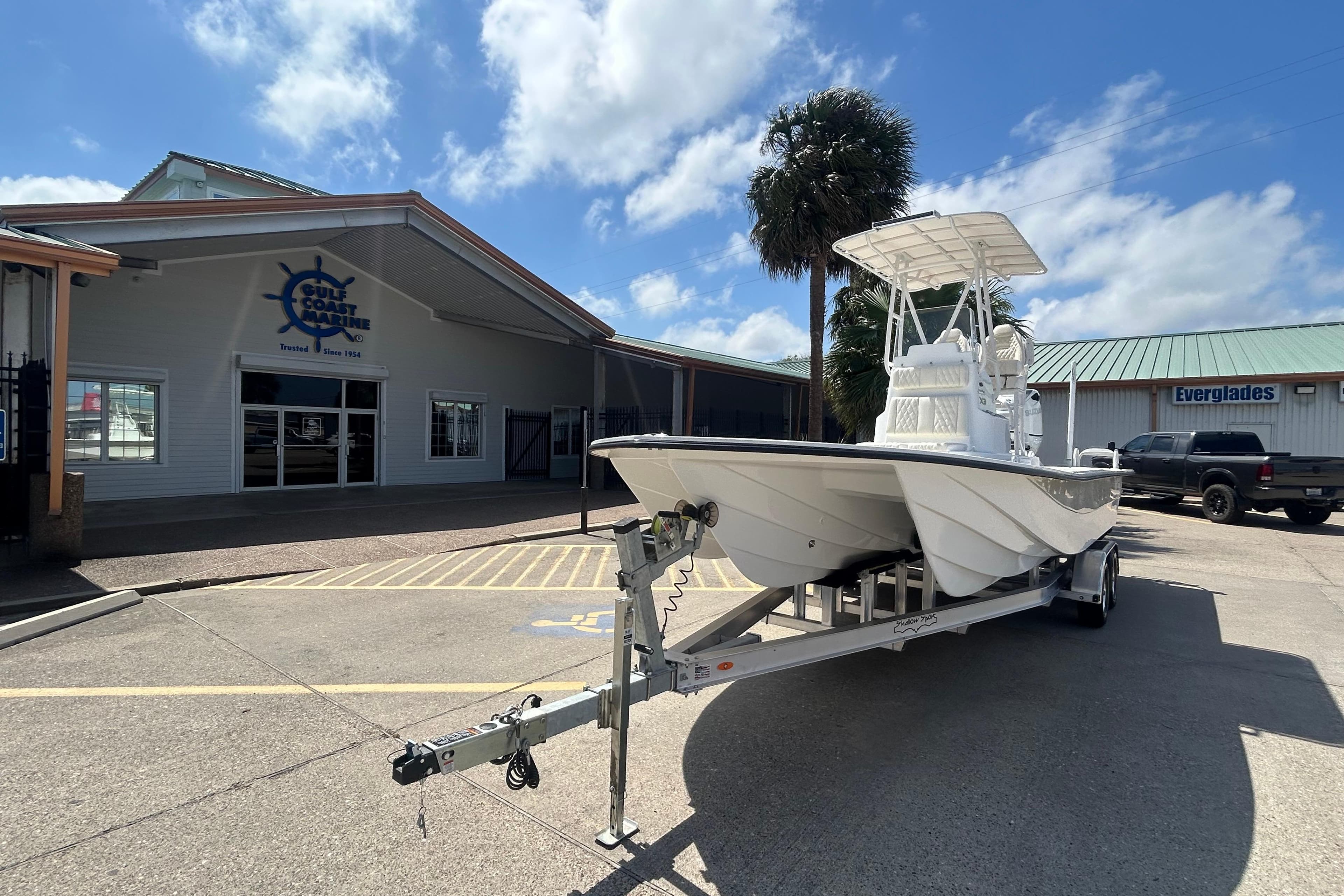 2026 Shallow Sport 25 X3 boat on trailer outside Gulf Coast Marine building.