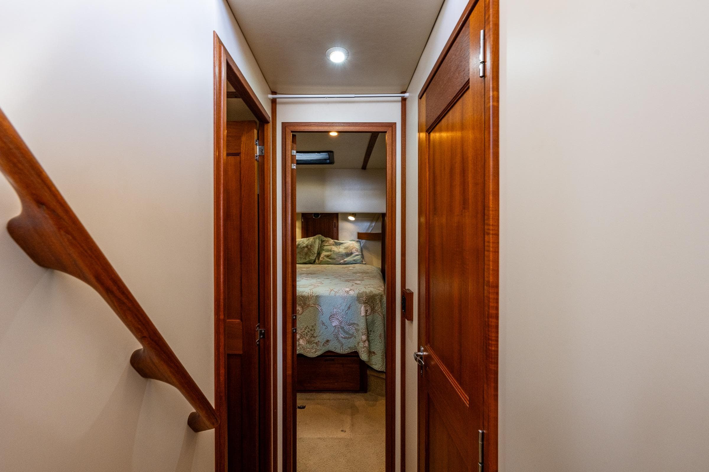 Interior hallway of 2003 Nordic Tug 37, featuring wooden doors and cozy bedroom view.