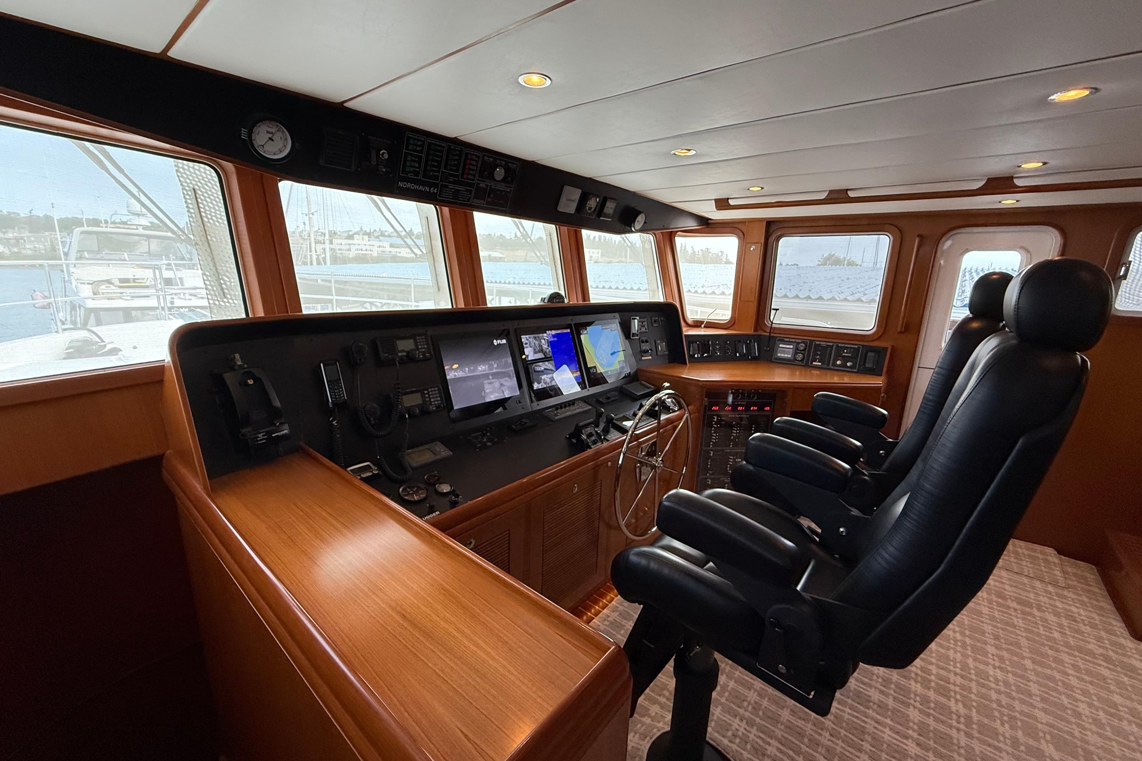 Pilothouse of 2009 Nordhavn N64 yacht with navigation equipment and leather chairs.