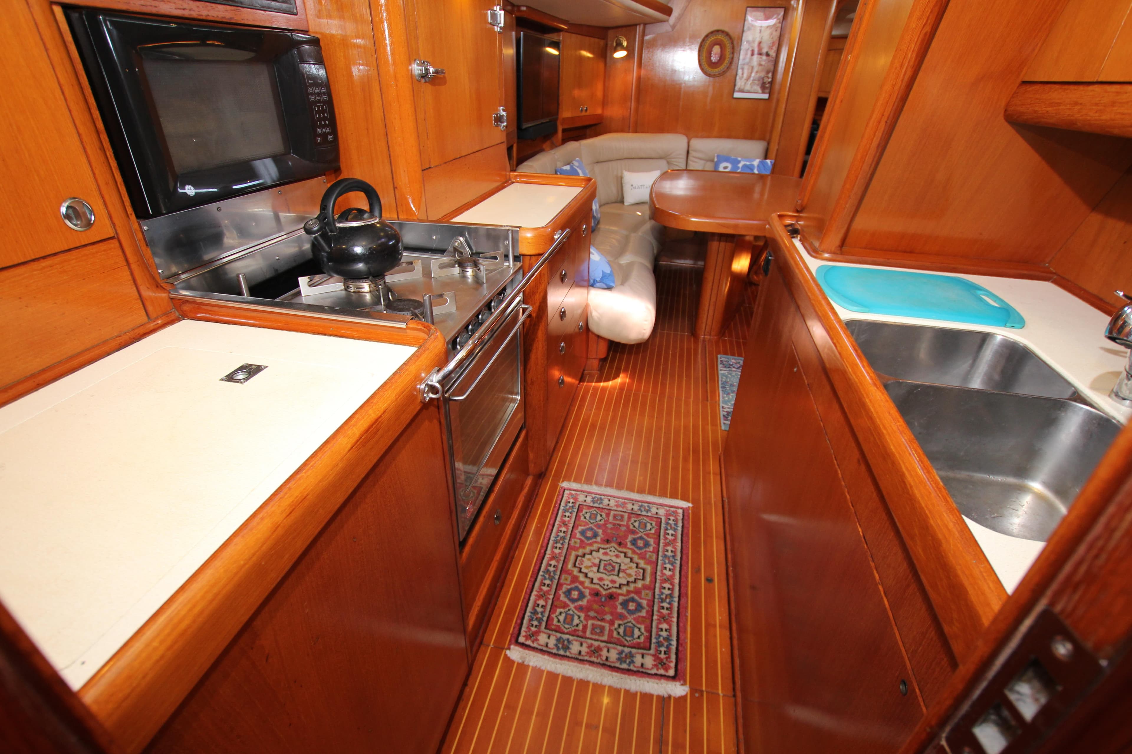 Luxurious 1997 Nautor Swan 48 yacht interior with wooden cabinetry and modern kitchen amenities.