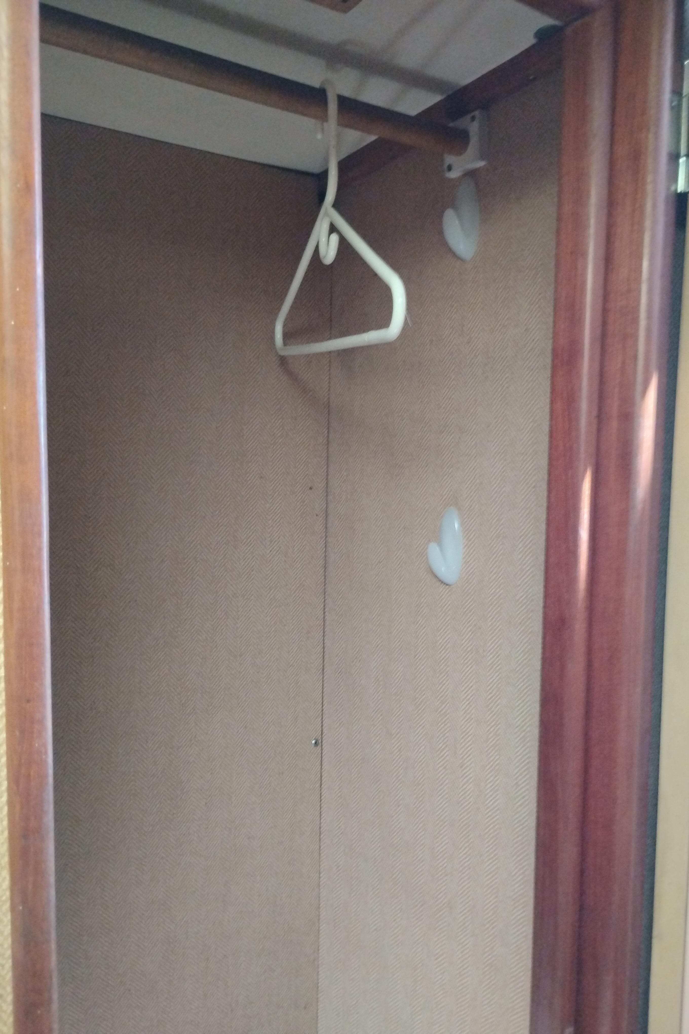 Empty closet with wooden frame and hanger inside a 1978 Bertram 33 Convertible boat.