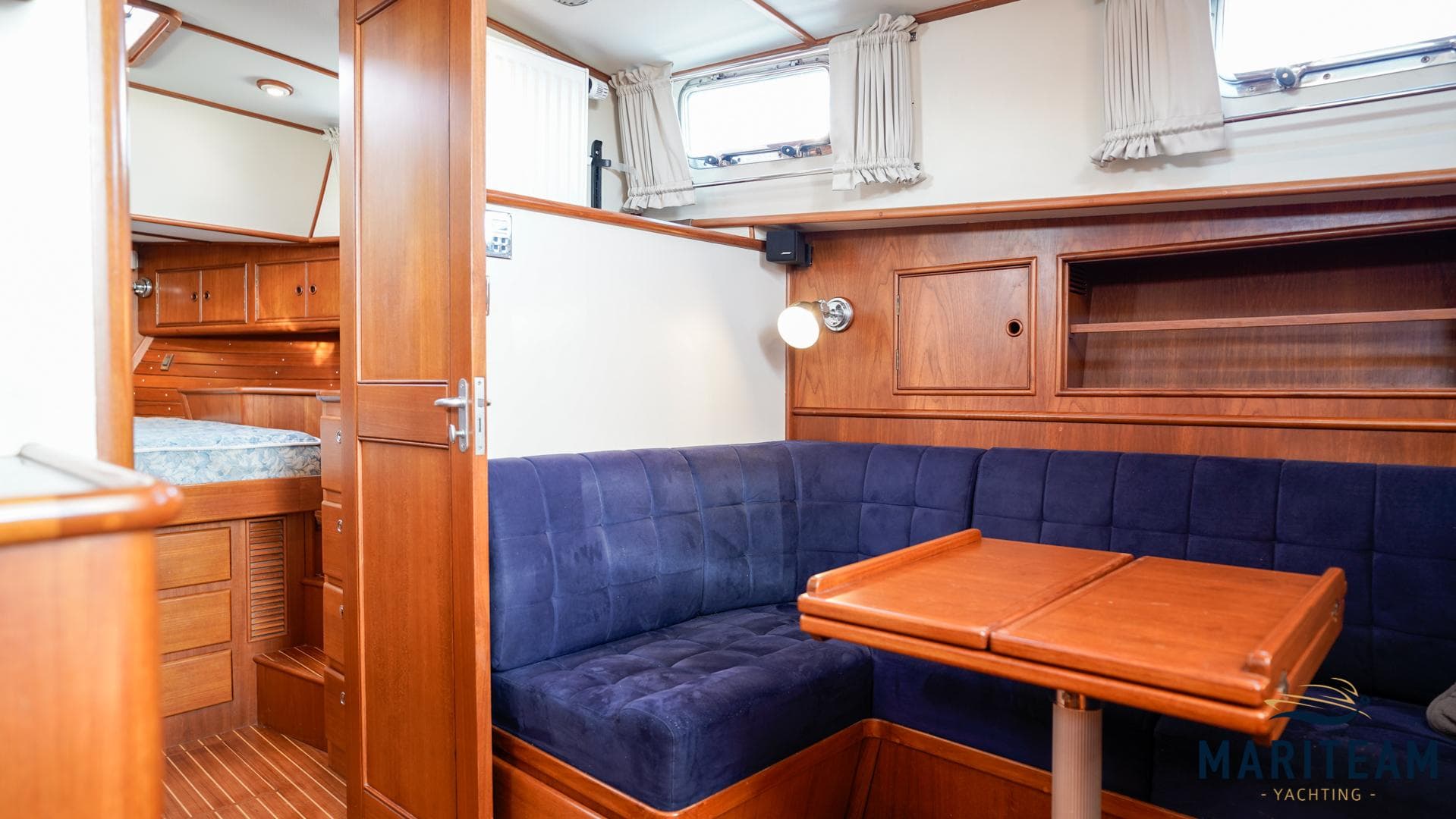 Interior of 2000 Grand Banks Eastbay 38 HX with blue seating and wooden table.