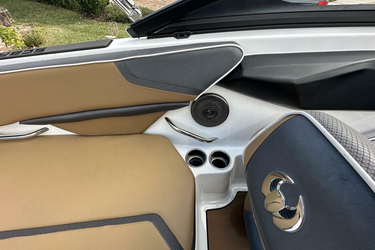 Interior of 2021 Scarab 215 boat with tan and black seating, cup holders, and speaker.