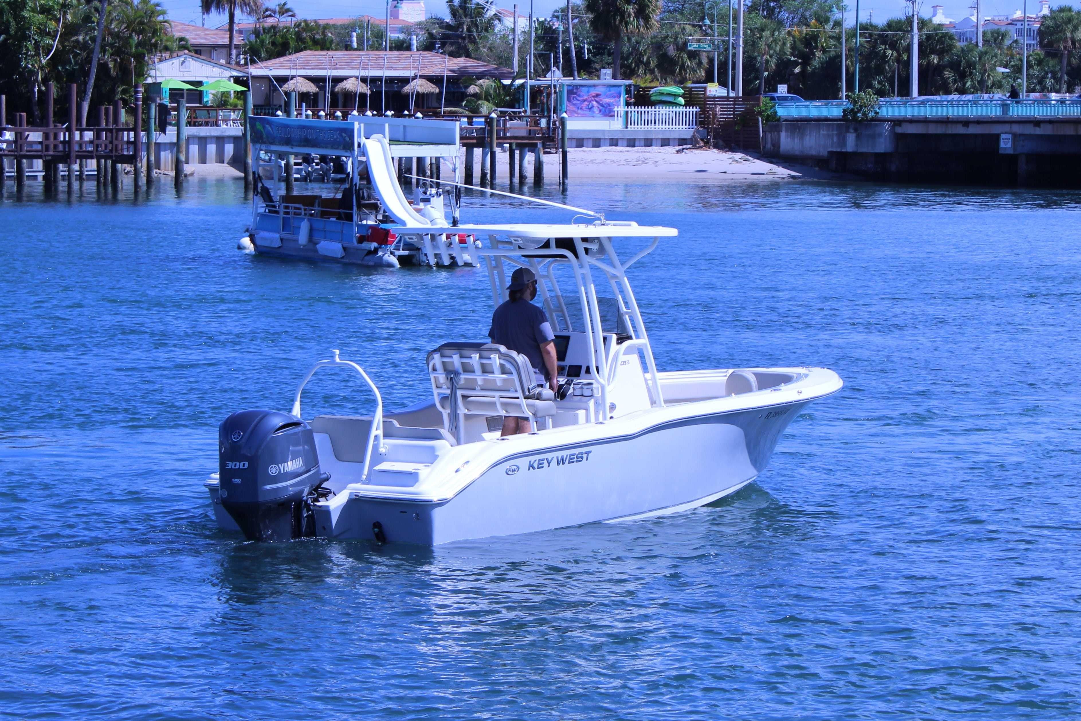 2021 Key West 239 FS boat cruising on clear blue water near a dock.