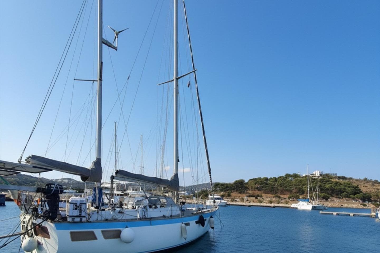 1978 Oyster 39 sailboat docked in a serene marina under a clear blue sky.