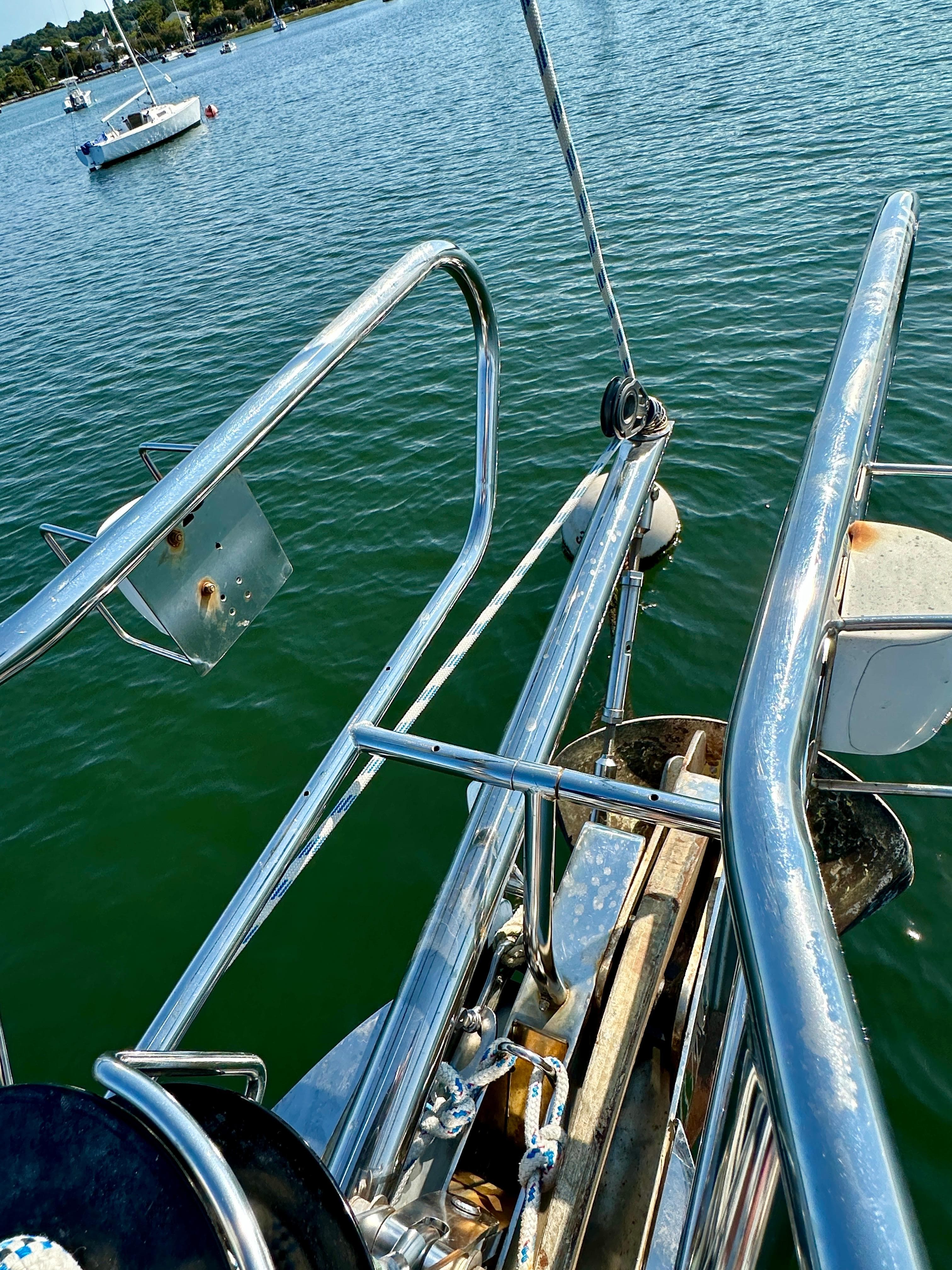 Bow of 2010 Beneteau 57 sailboat with stainless steel railings on calm water.