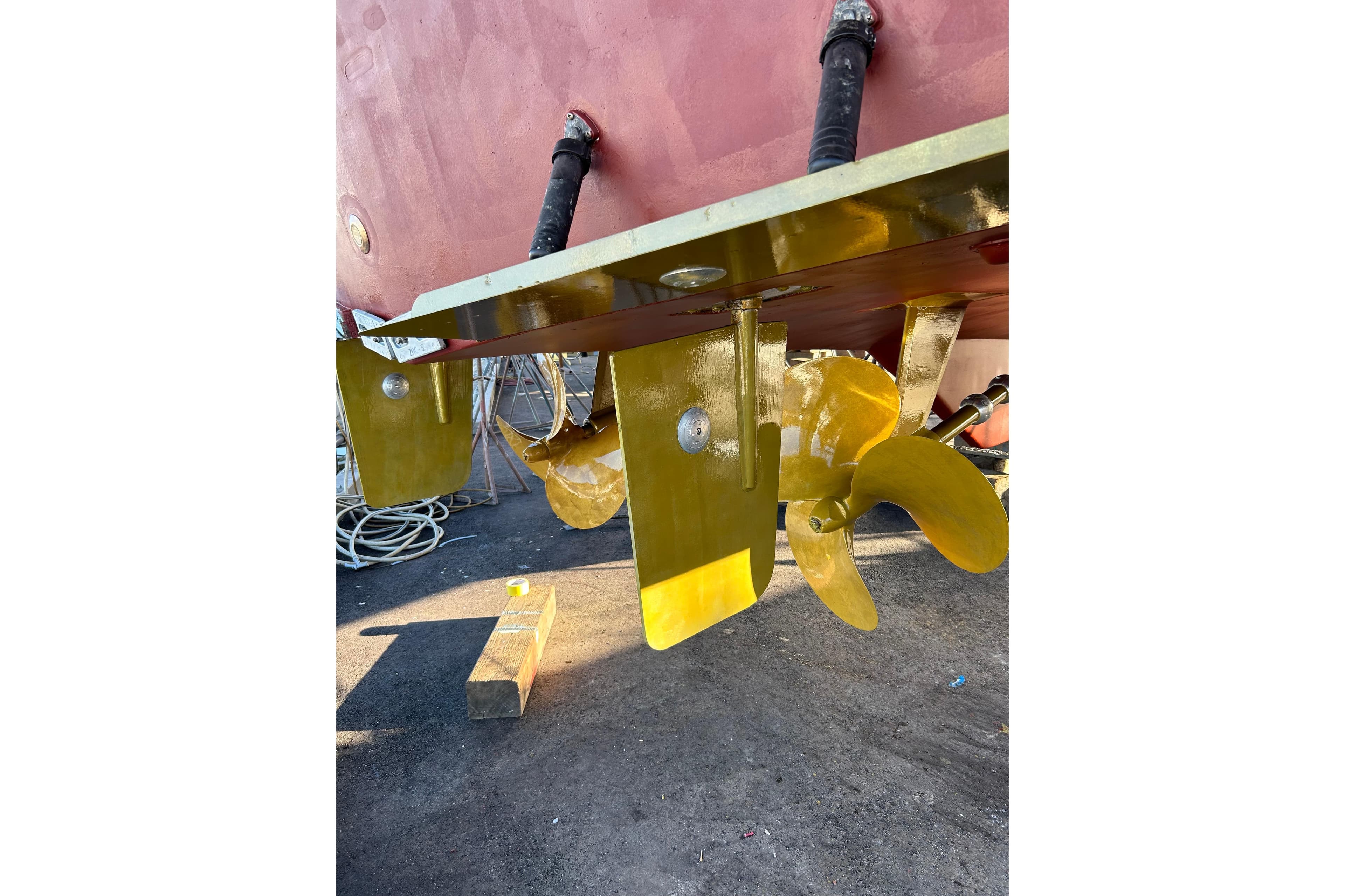 Yellow boat propeller and rudder of a 1999 Symbol 58 model, dockside view.