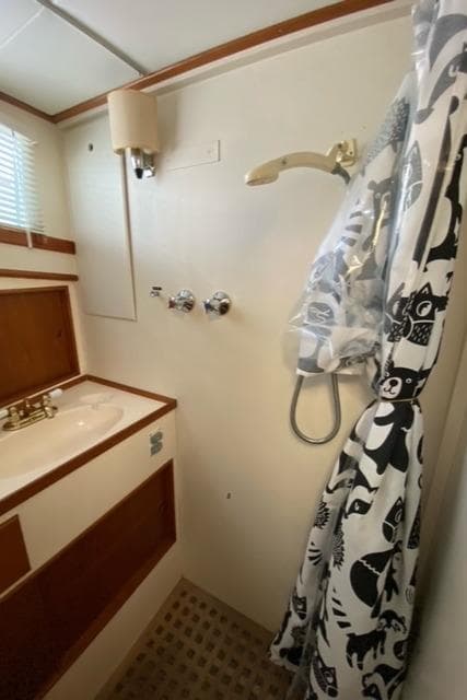 1977 Grand Banks 42 bathroom with shower, sink, and patterned curtain.
