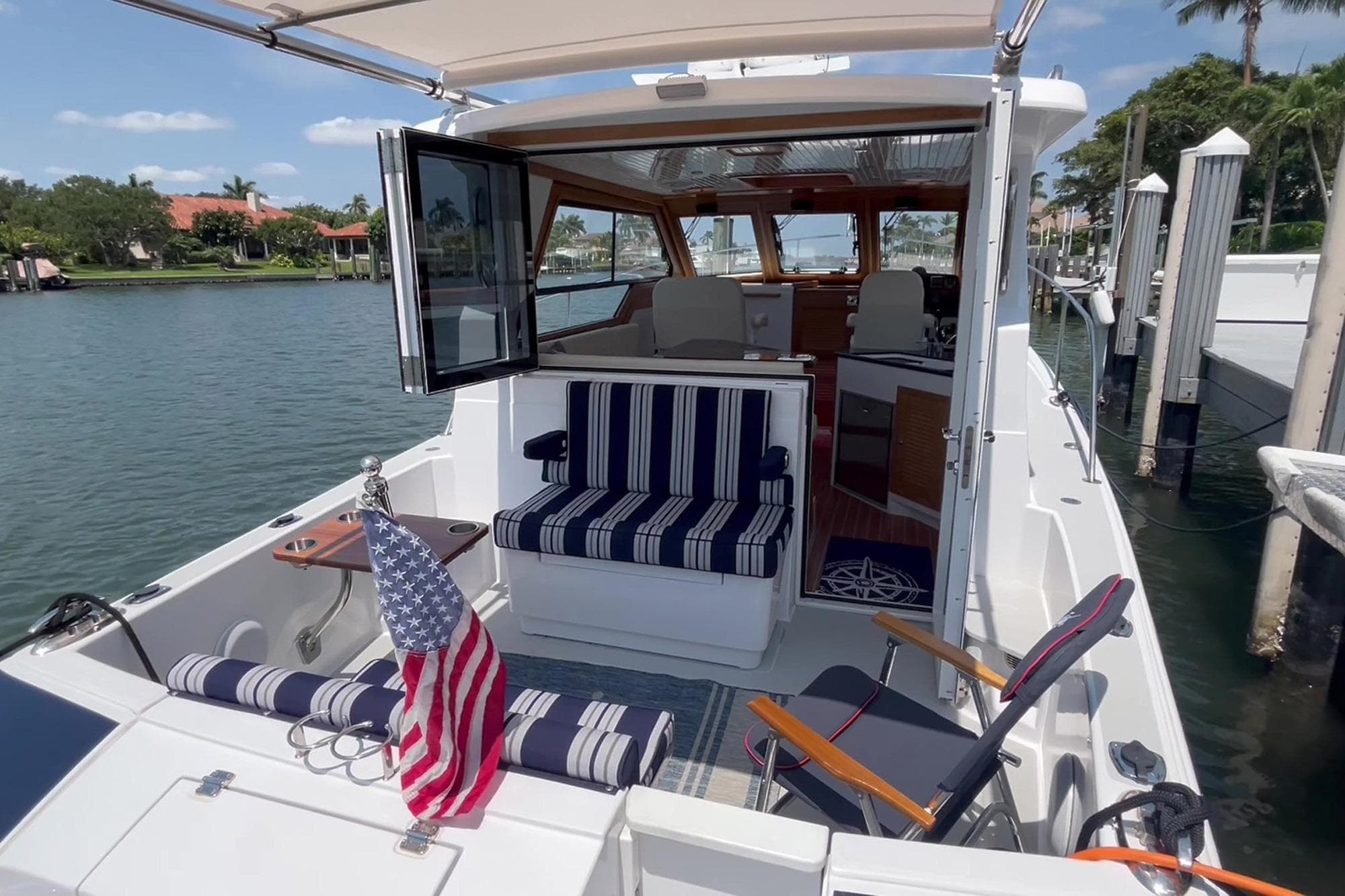 2024 True North 34 Outboard Express boat with striped seating and American flag at dock.