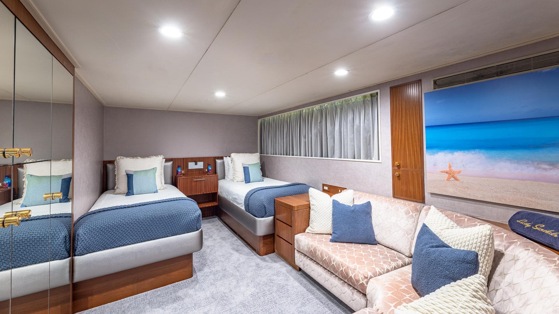 Luxurious yacht cabin with twin beds, sofa, and beach-themed decor, Feadship Custom 1985.