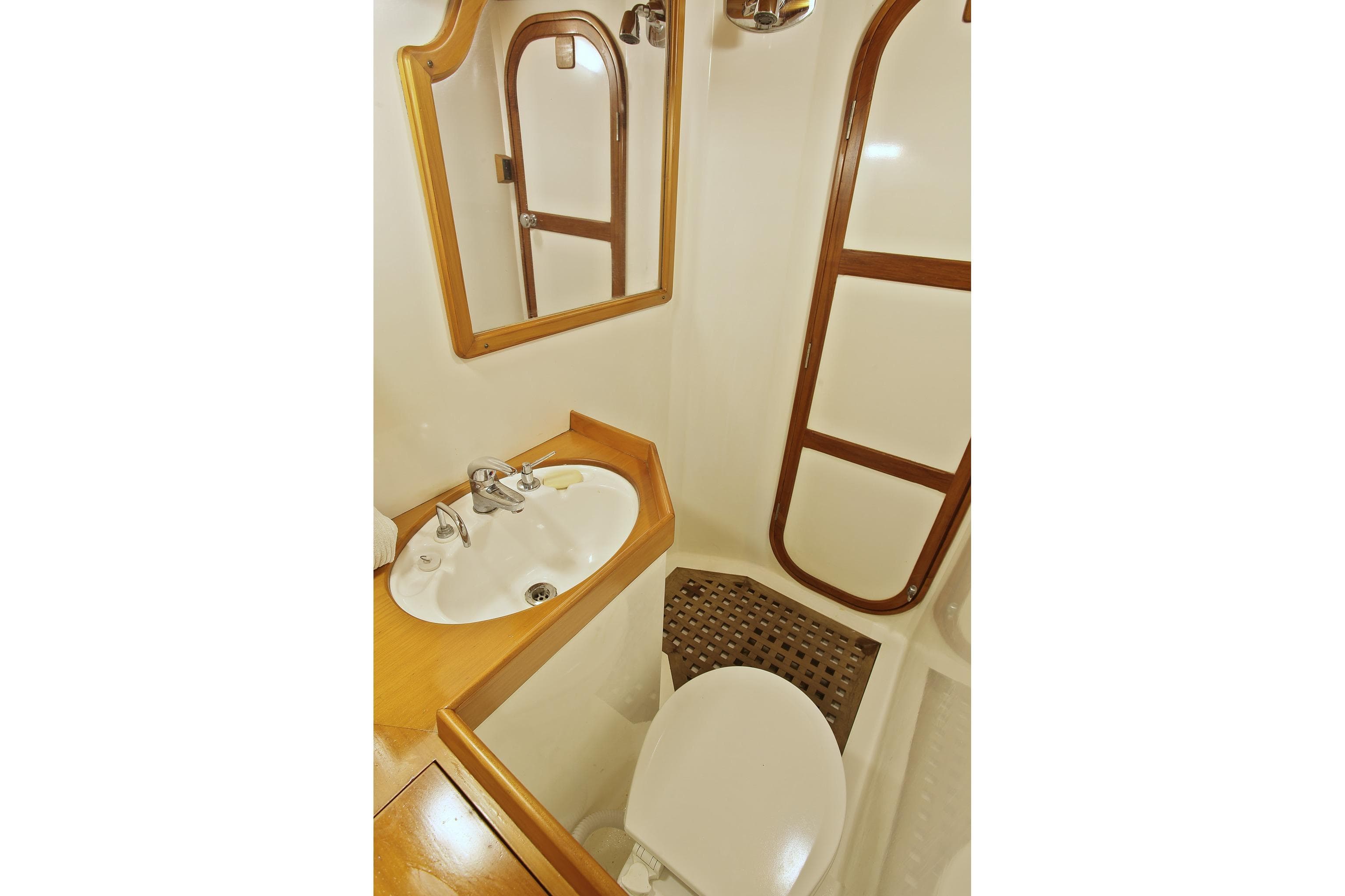 Bathroom interior of 1986 Davidson 47 yacht with sink, mirror, and wooden accents.