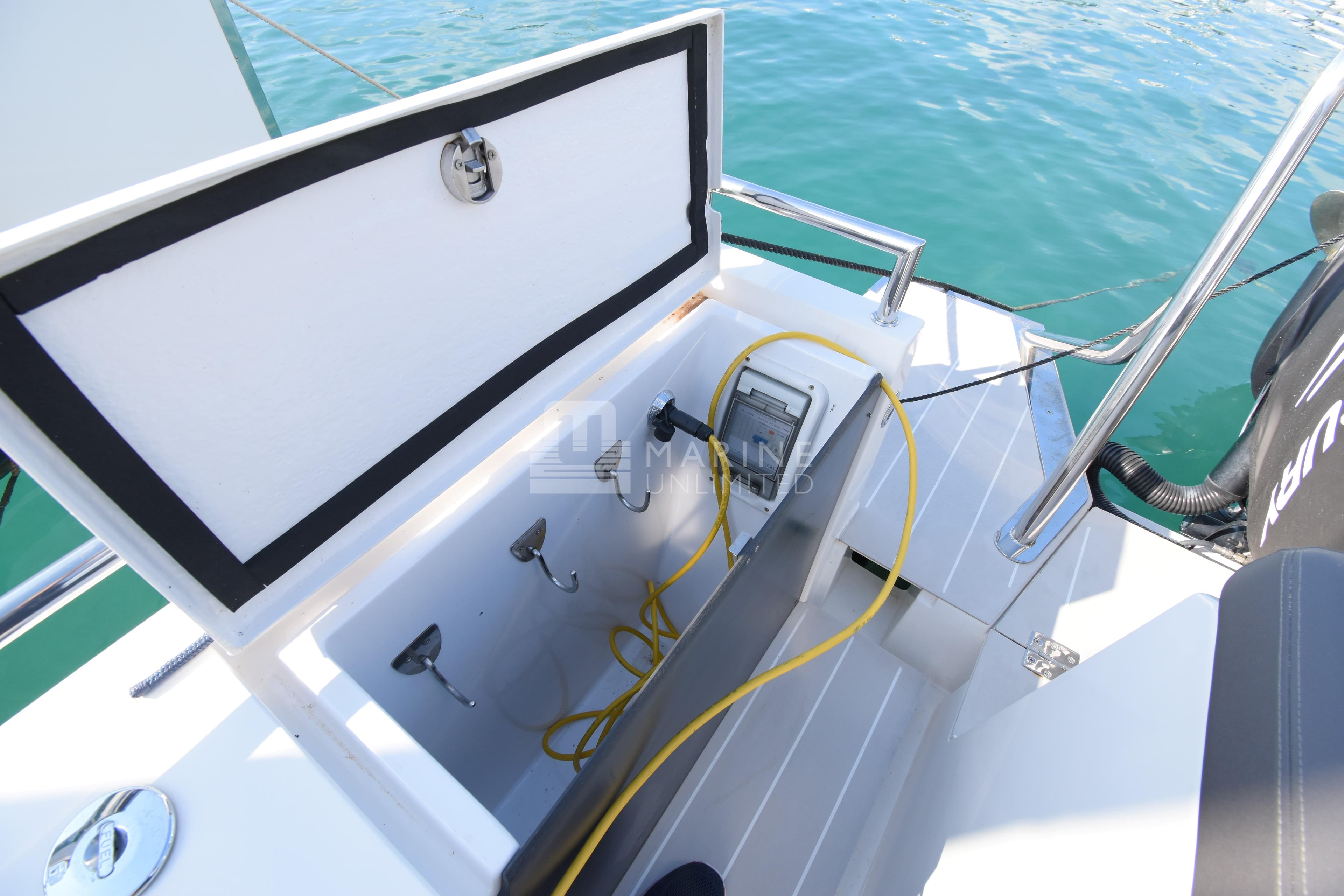 Open storage compartment on 2016 Axopar 37 Sun-Top boat, featuring hooks and yellow cable.