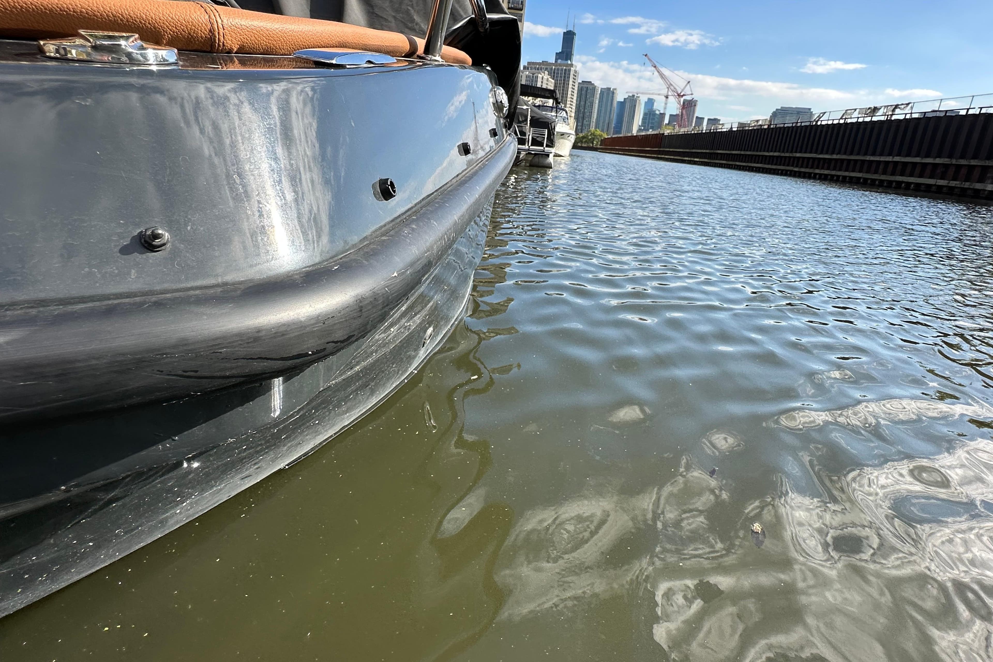 2023 Magonis Wave E-550 boat on urban waterway with city skyline.