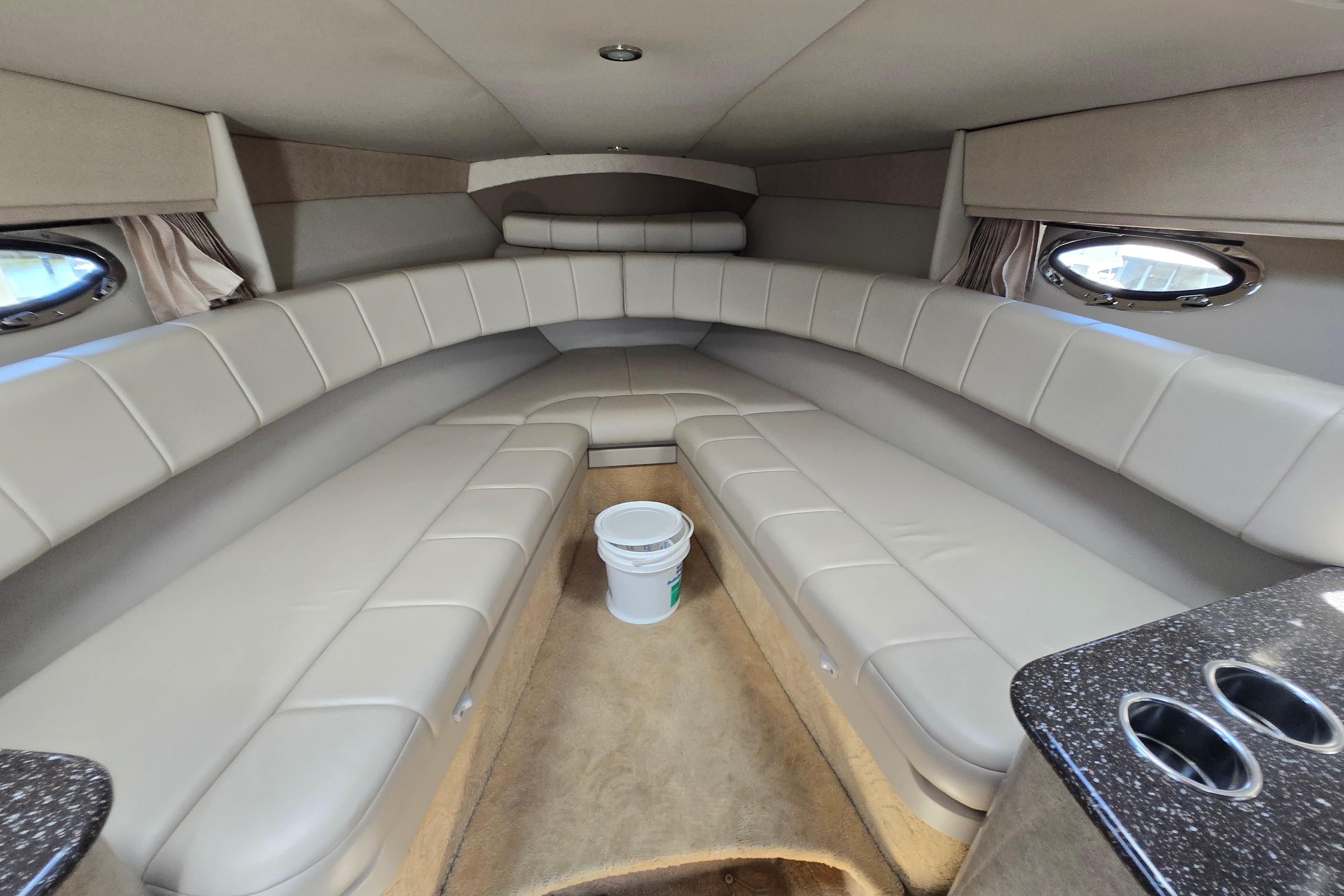 Interior of a 2005 Formula 330 Sun Sport boat with beige seating and porthole windows.
