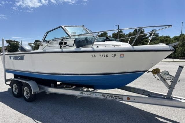 1989 Pursuit 2260 Denali boat on trailer, parked outdoors under clear sky.