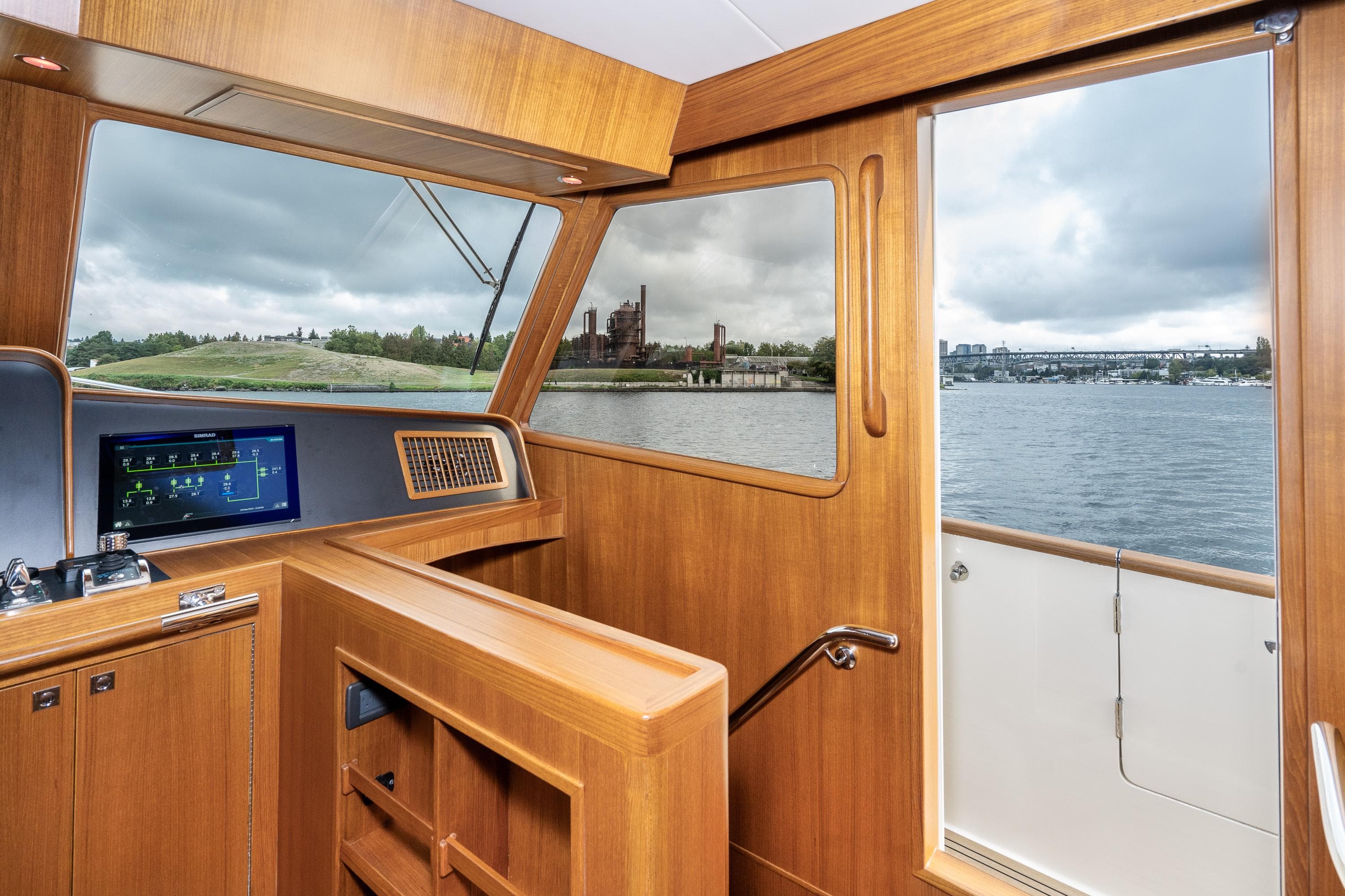 2024 Fleming 58 Pilothouse interior with wood finish, navigation screen, and scenic water view.