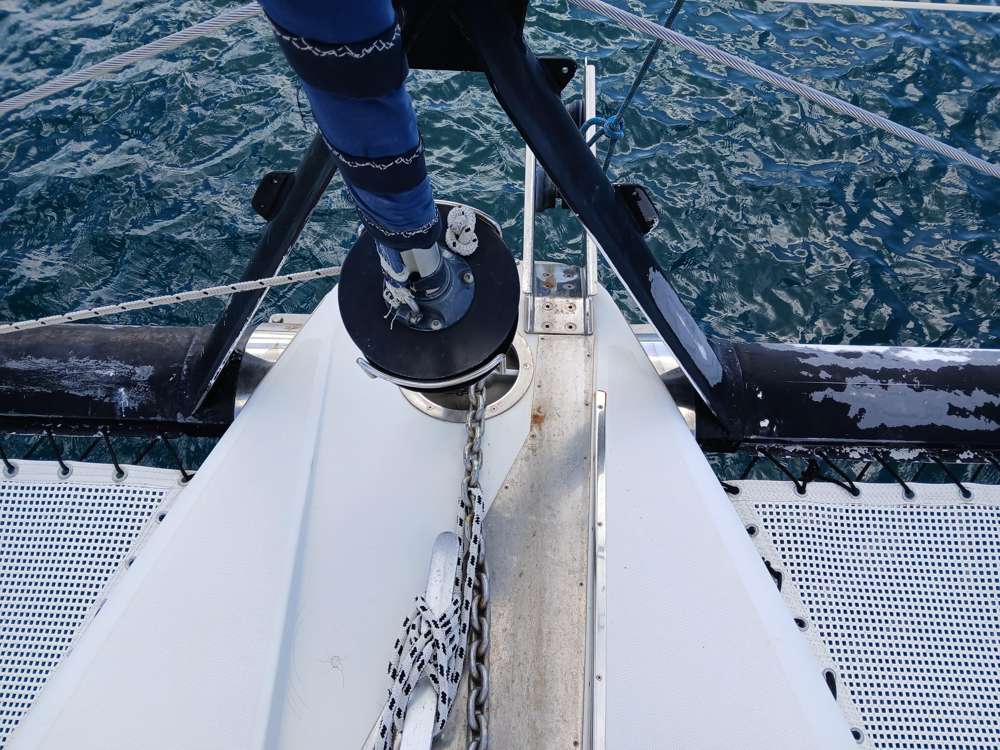 Bow of Privilege 37 catamaran, 2000 model, with anchor chain over blue ocean.