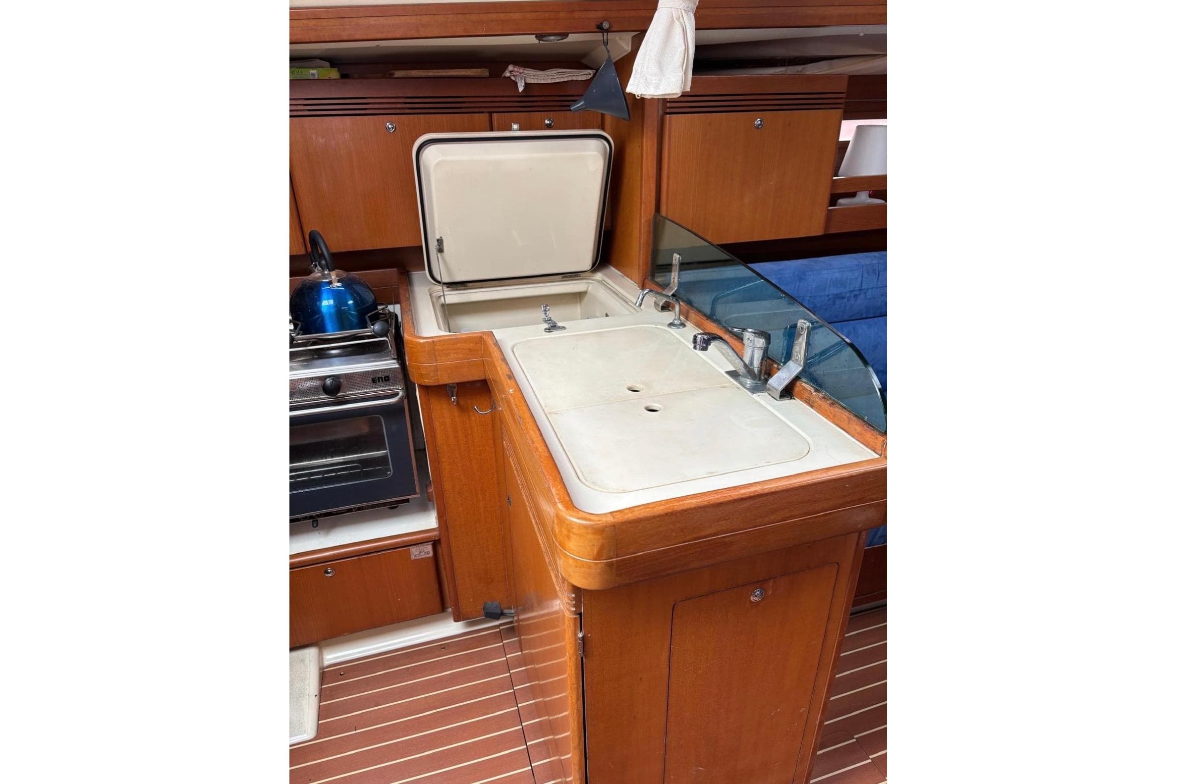 2005 Dufour 34 Performance yacht kitchen with stove, sink, and wooden cabinetry.