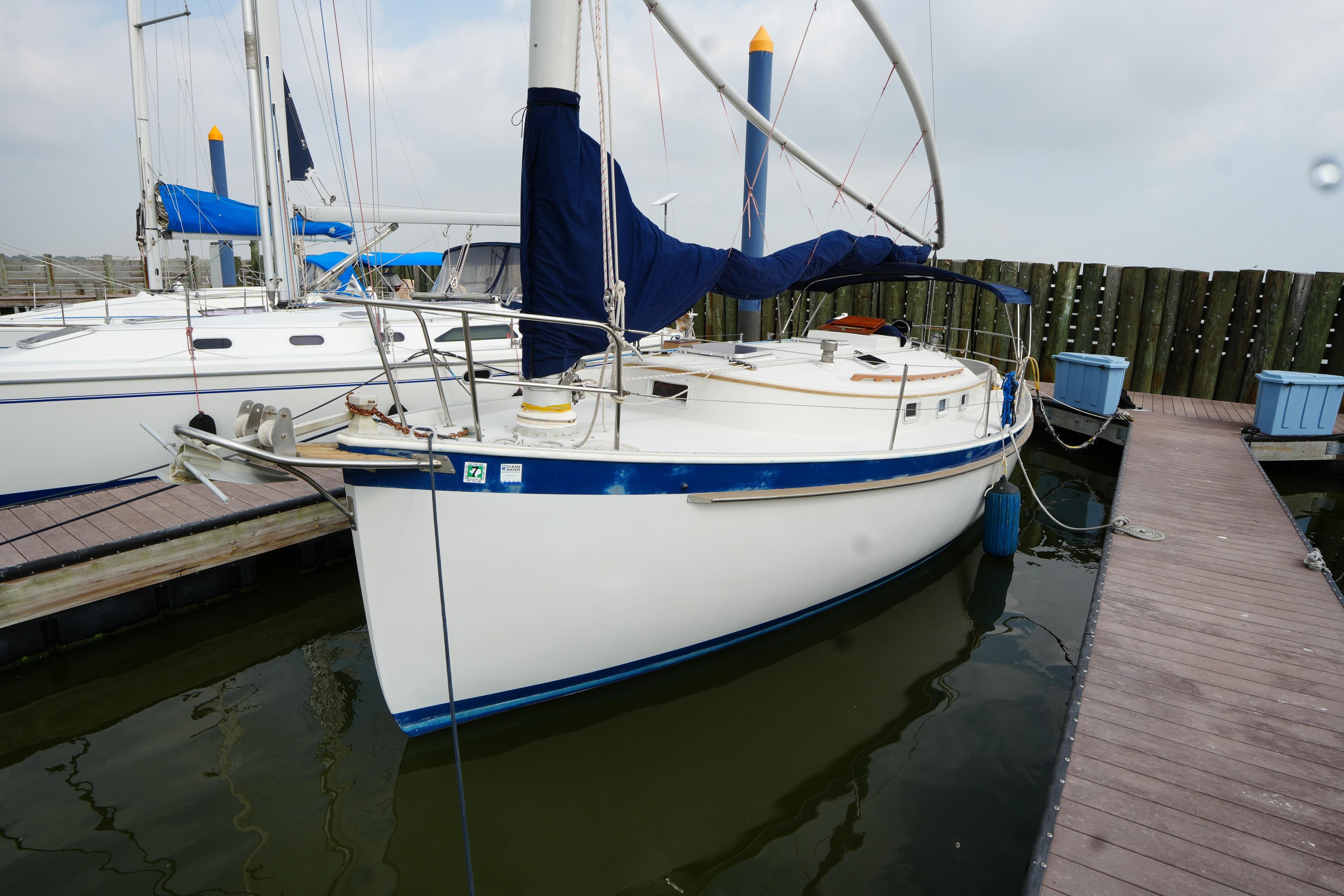 1988 Nonsuch 30 Ultra sailboat docked at marina, featuring blue accents and covered sails.