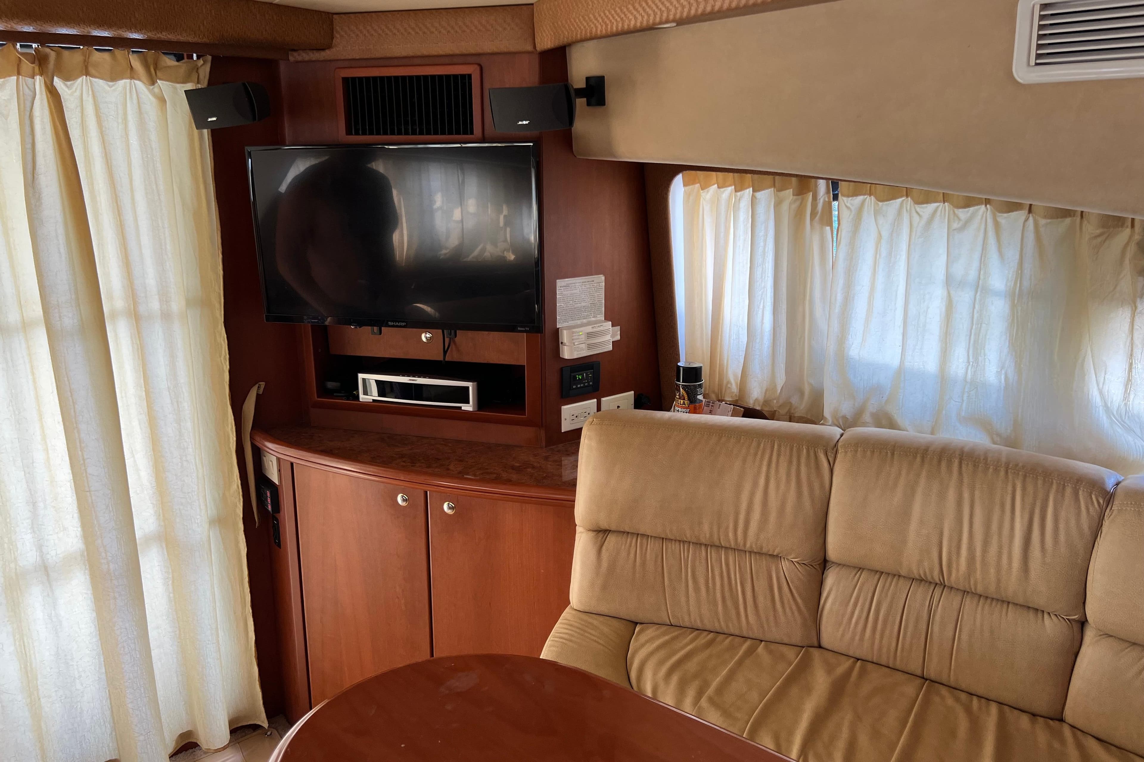Interior of 2006 Silverton 38 Sport Bridge with TV, beige sofa, and wooden cabinetry.