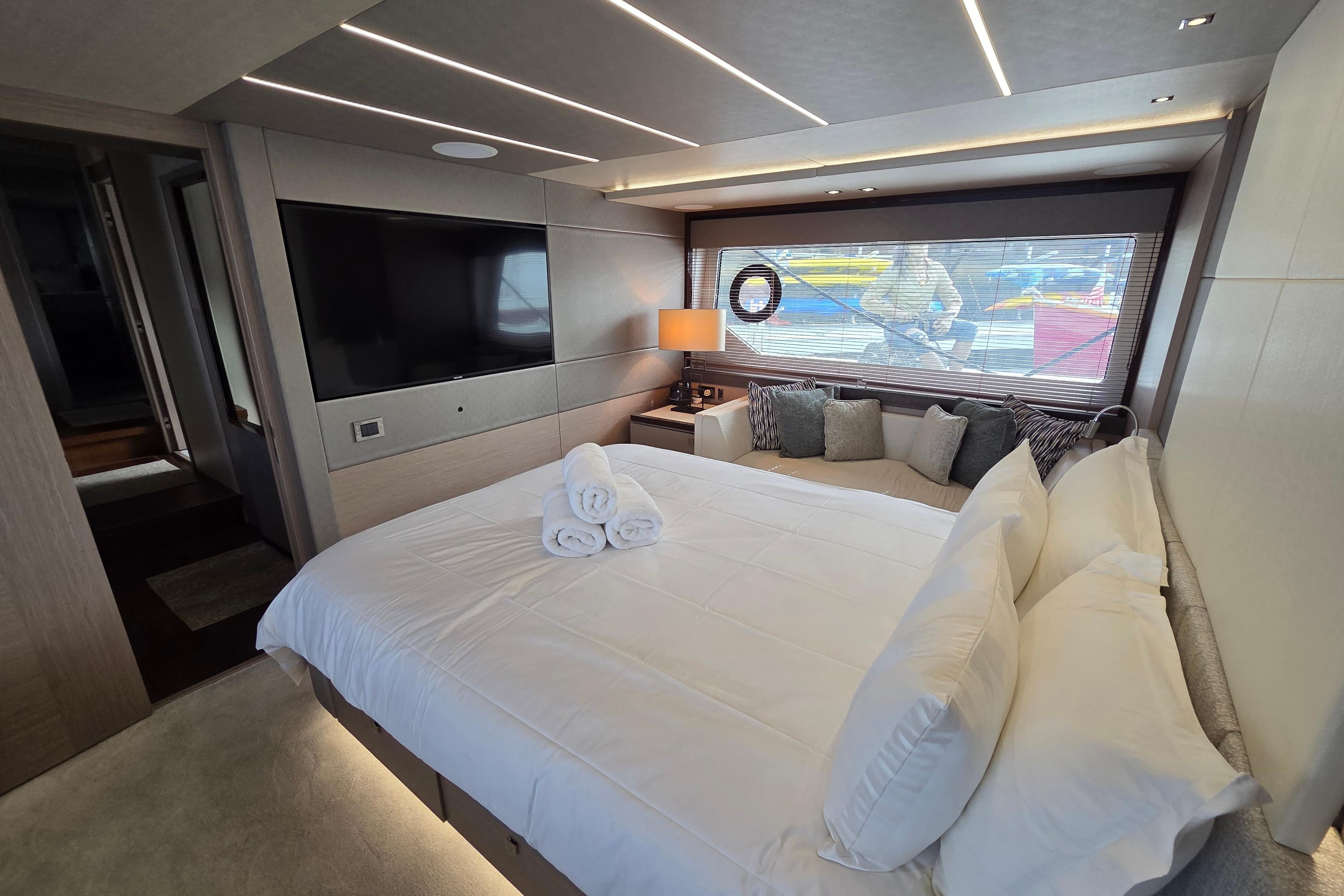 Luxurious bedroom interior of 2018 Sunseeker 76 Yacht with modern decor and large window.