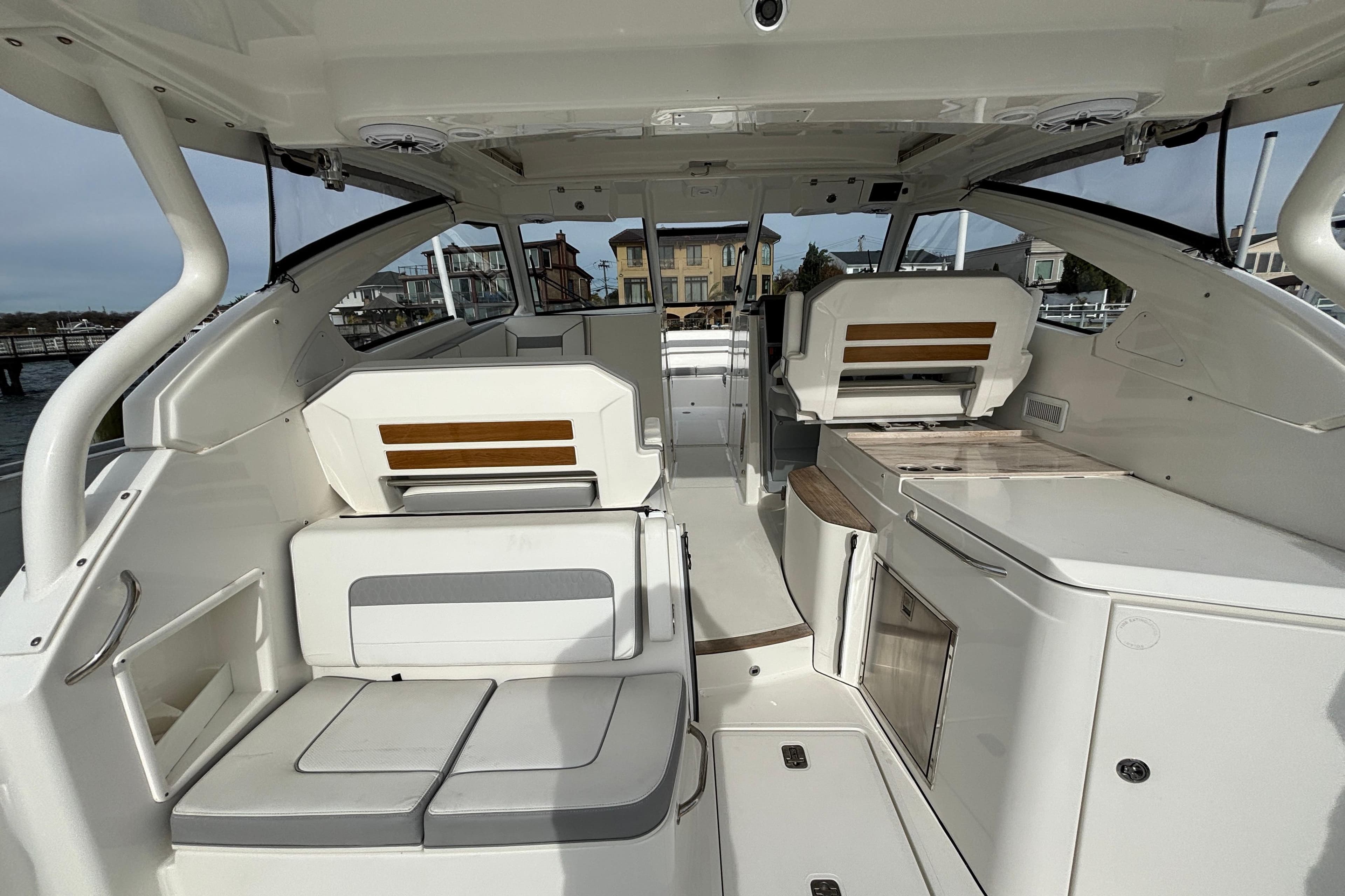 2022 Pursuit DC 365 Dual Console interior with seating and storage, docked near waterfront homes.