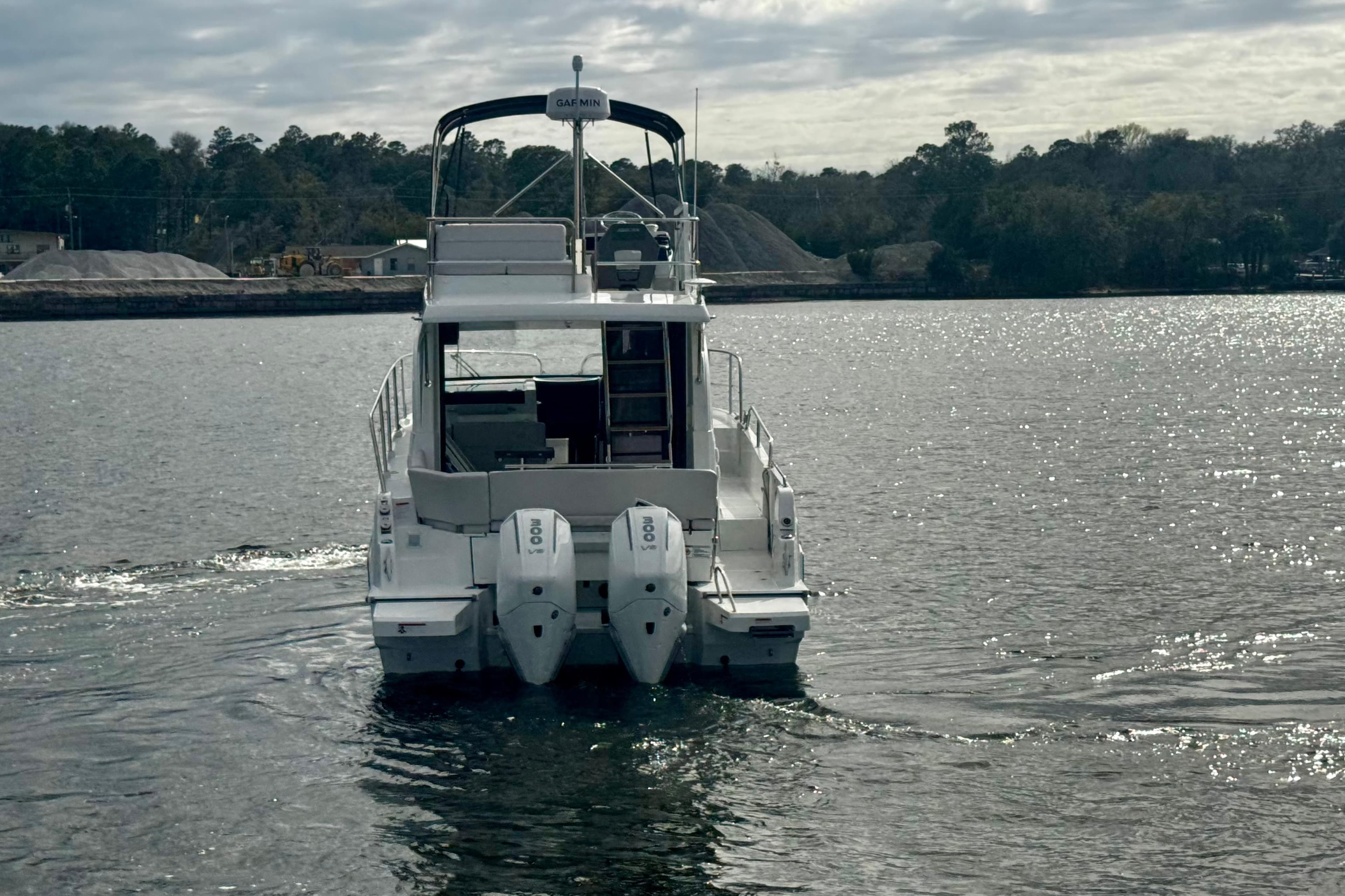 2026 Beneteau Antares 11 Fly cruising on a serene lake under a cloudy sky.