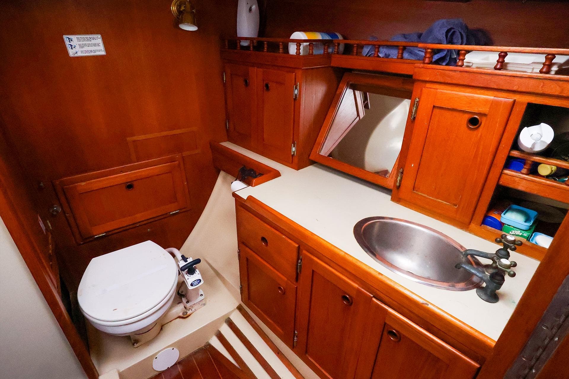 1985 Bayfield 40 yacht bathroom with wooden cabinets, sink, and toilet.