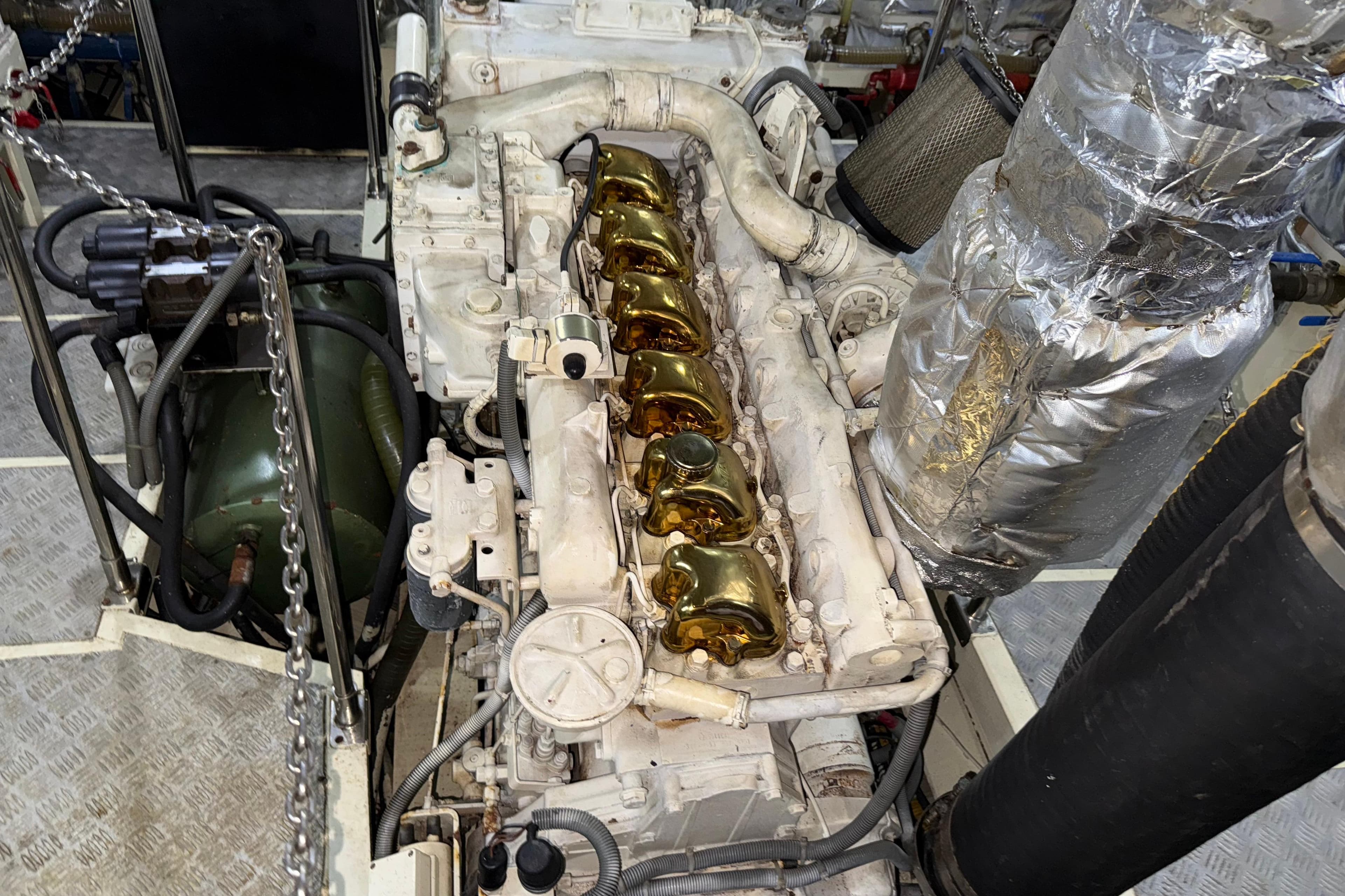 Engine room of a 1999 Mercan 23M Yacht with visible components and metallic details.