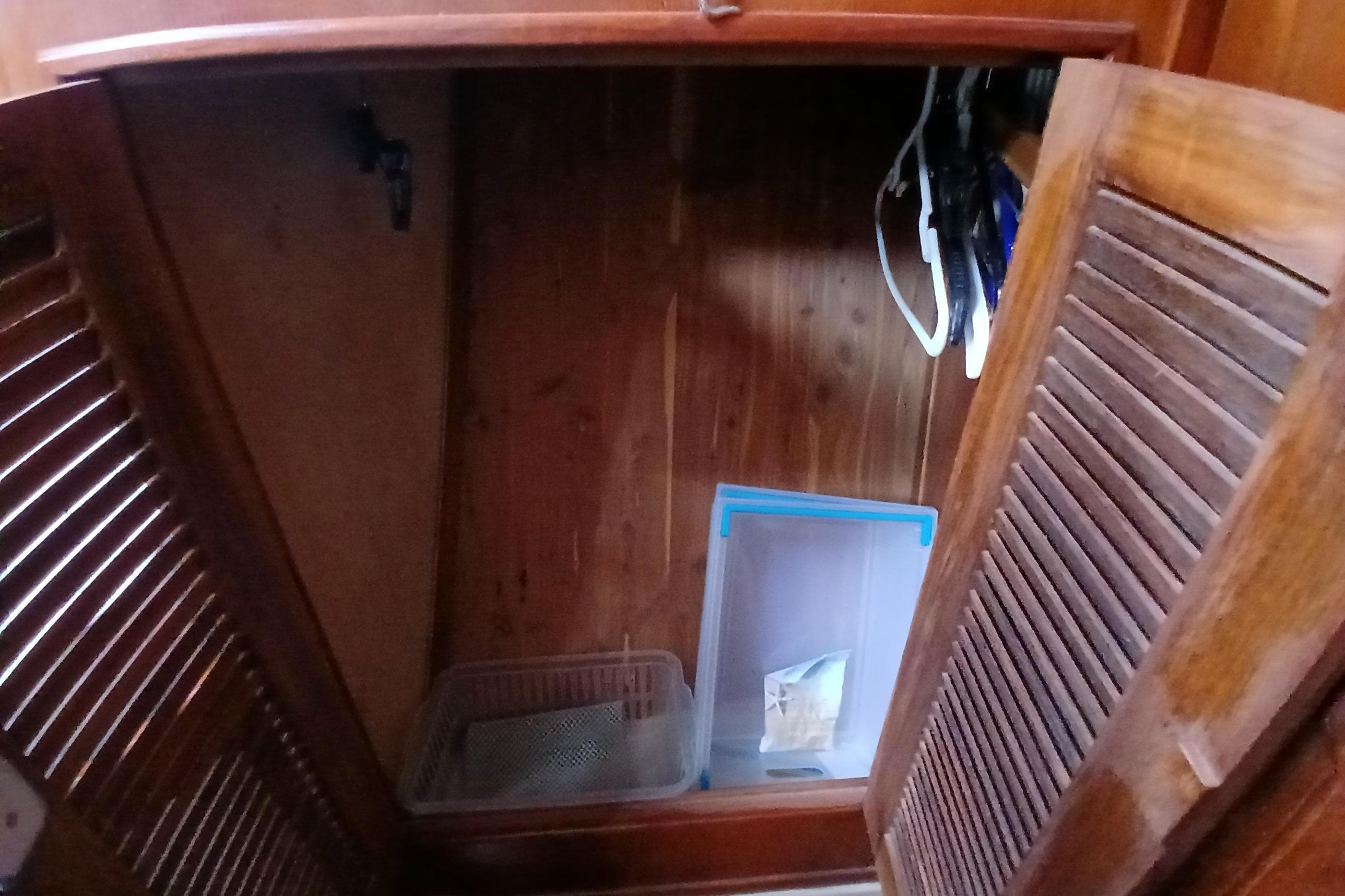 Wooden cabinet interior on a 1995 Island Packet 37 sailboat, featuring storage items.