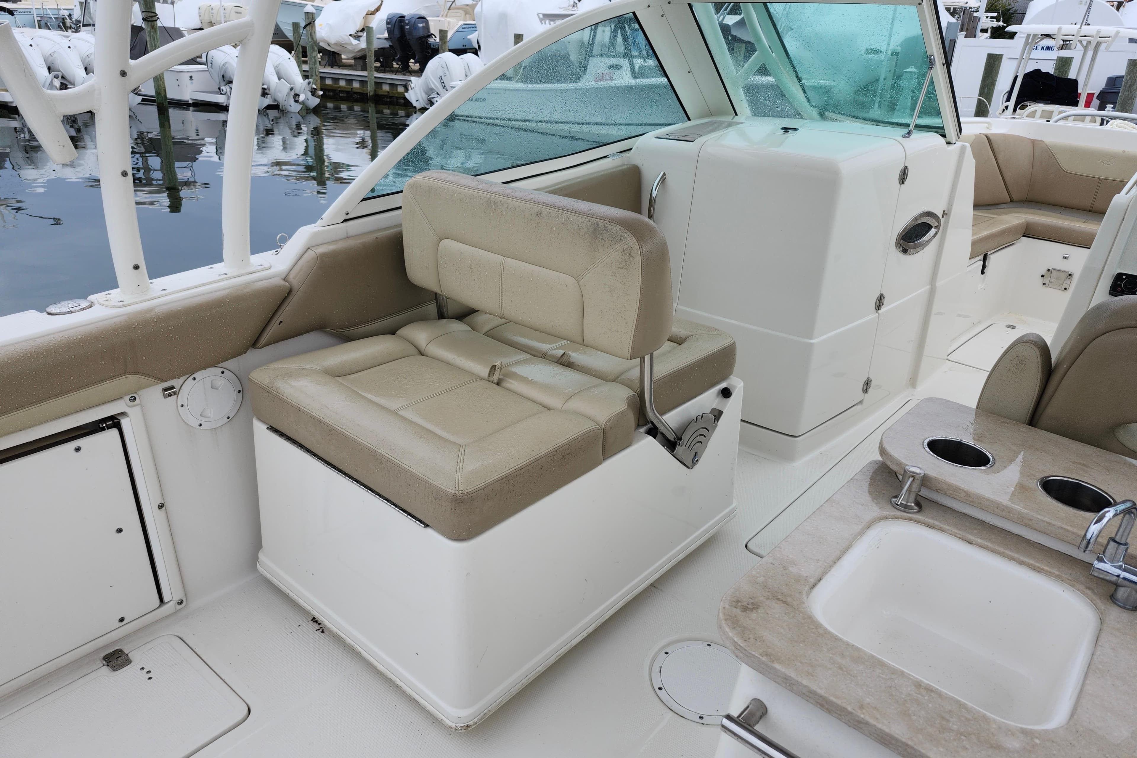 2017 Sailfish 275 DC boat interior with beige seating and a small sink area.