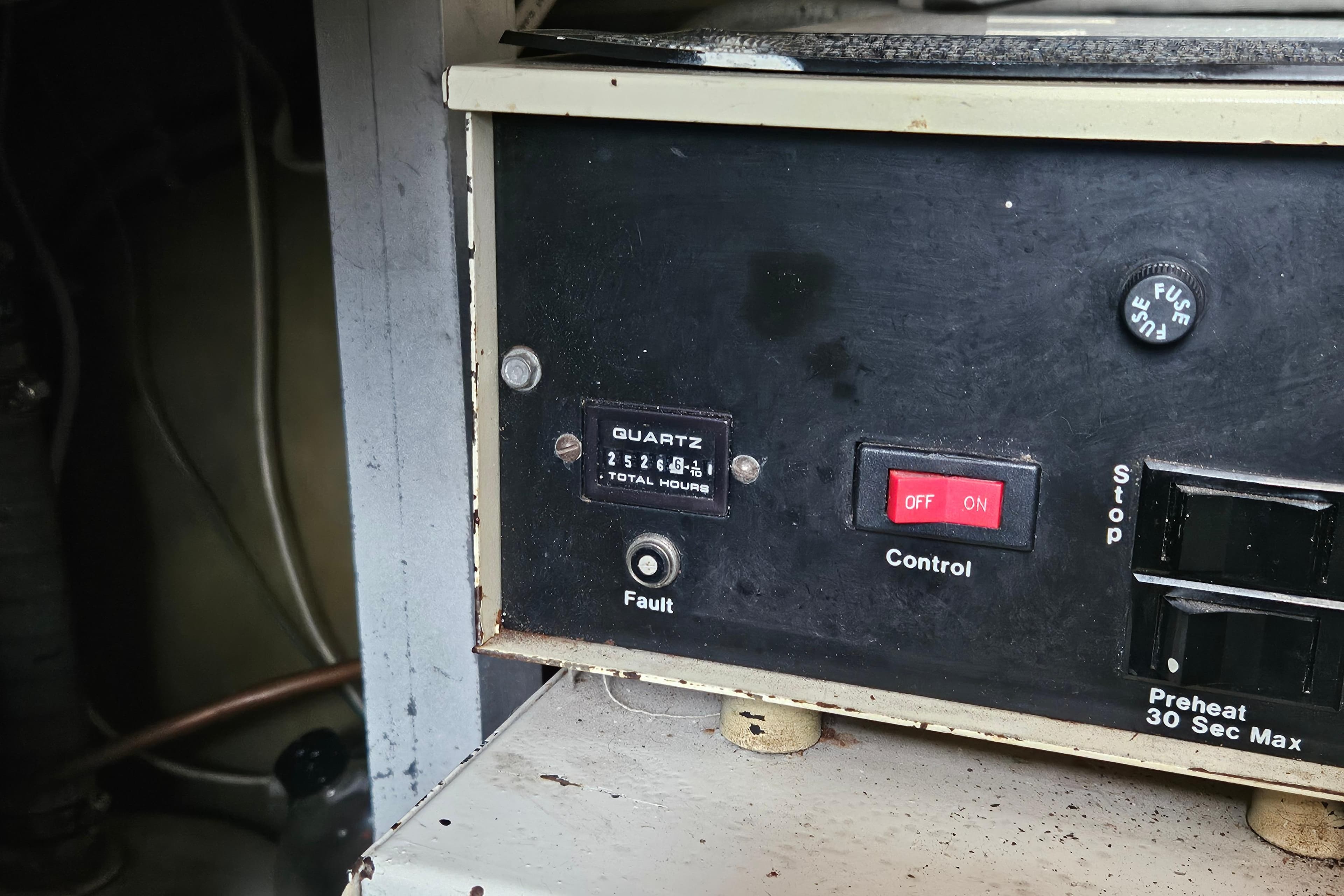 Control panel of a 1985 Post 43 Convertible with switches and hour meter.
