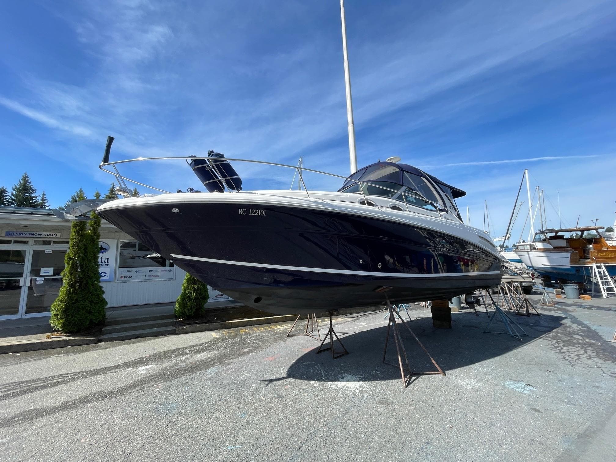 2006 Sea Ray 300 Sundancer boat on stands at a marina under a clear blue sky.