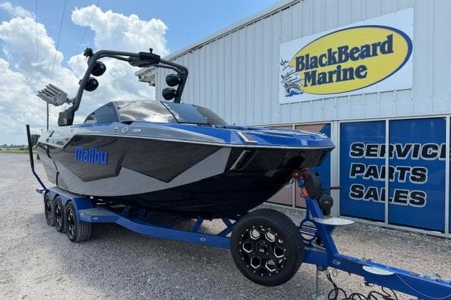 2024 Malibu M240 boat on trailer at BlackBeard Marine dealership, showcasing sleek design.