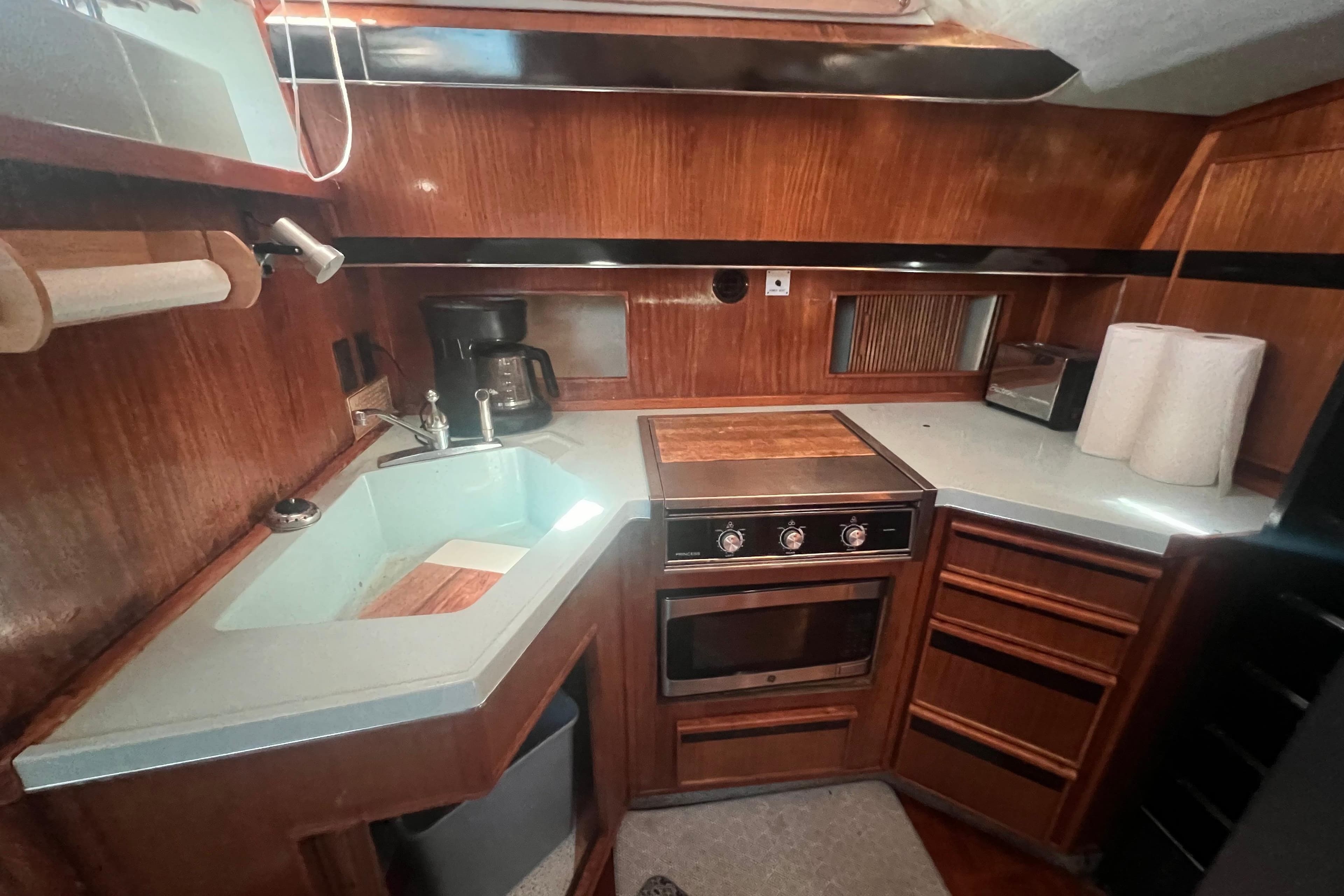 1987 Sea Ray 410 Aft Cabin kitchen with wood cabinetry, sink, stove, and appliances.