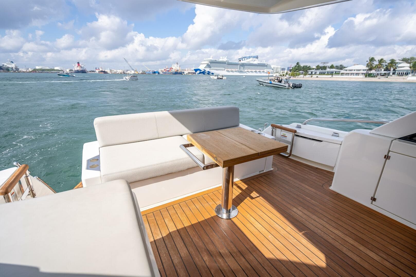 2021 Maritimo X50 yacht deck with seating and table, overlooking a scenic harbor.