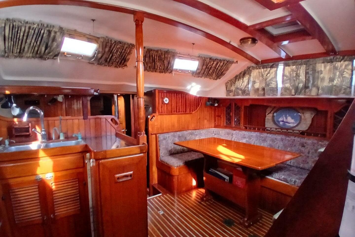 Interior of a 1980 Hardin 45 sailboat with wooden furnishings and cozy seating area.