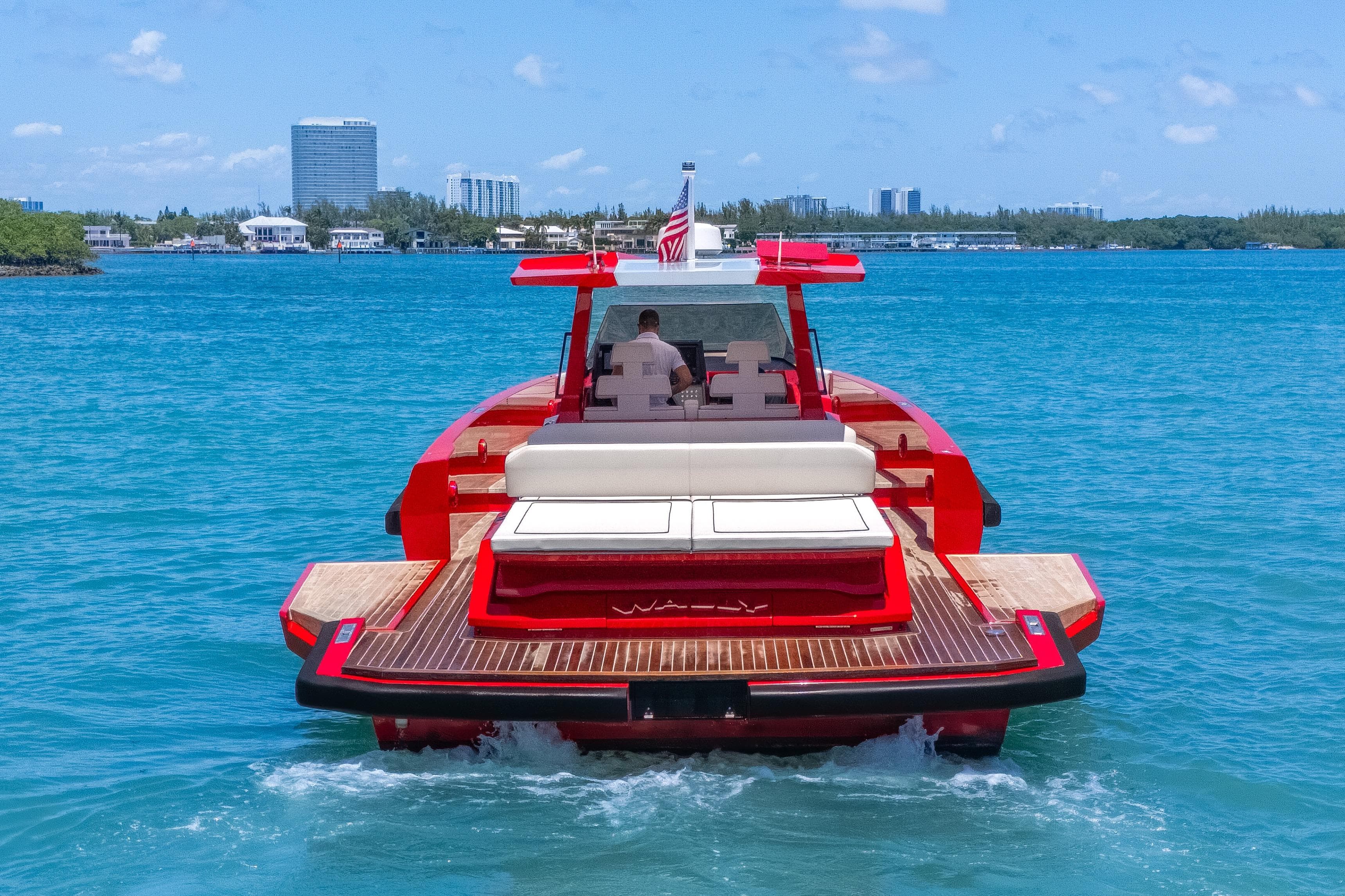 Red 2021 Wally 48 yacht cruising on blue waters near a city skyline.