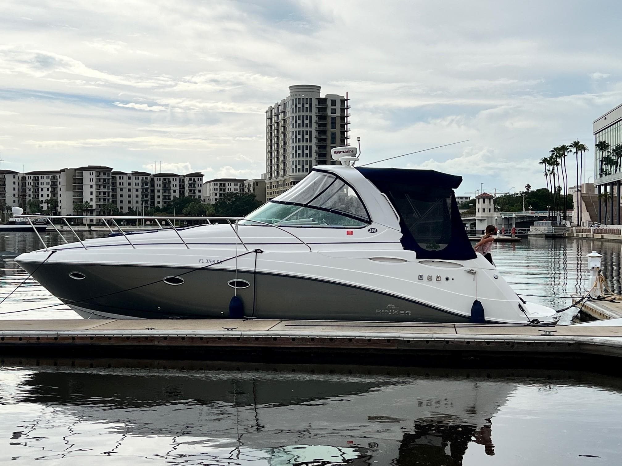 2008 Rinker 350 Express Cruiser docked in a marina with cityscape background.