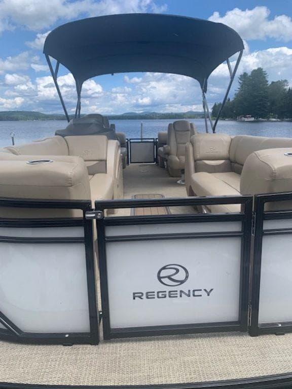 2020 Regency 230 DL3 pontoon boat with canopy on a serene lake.