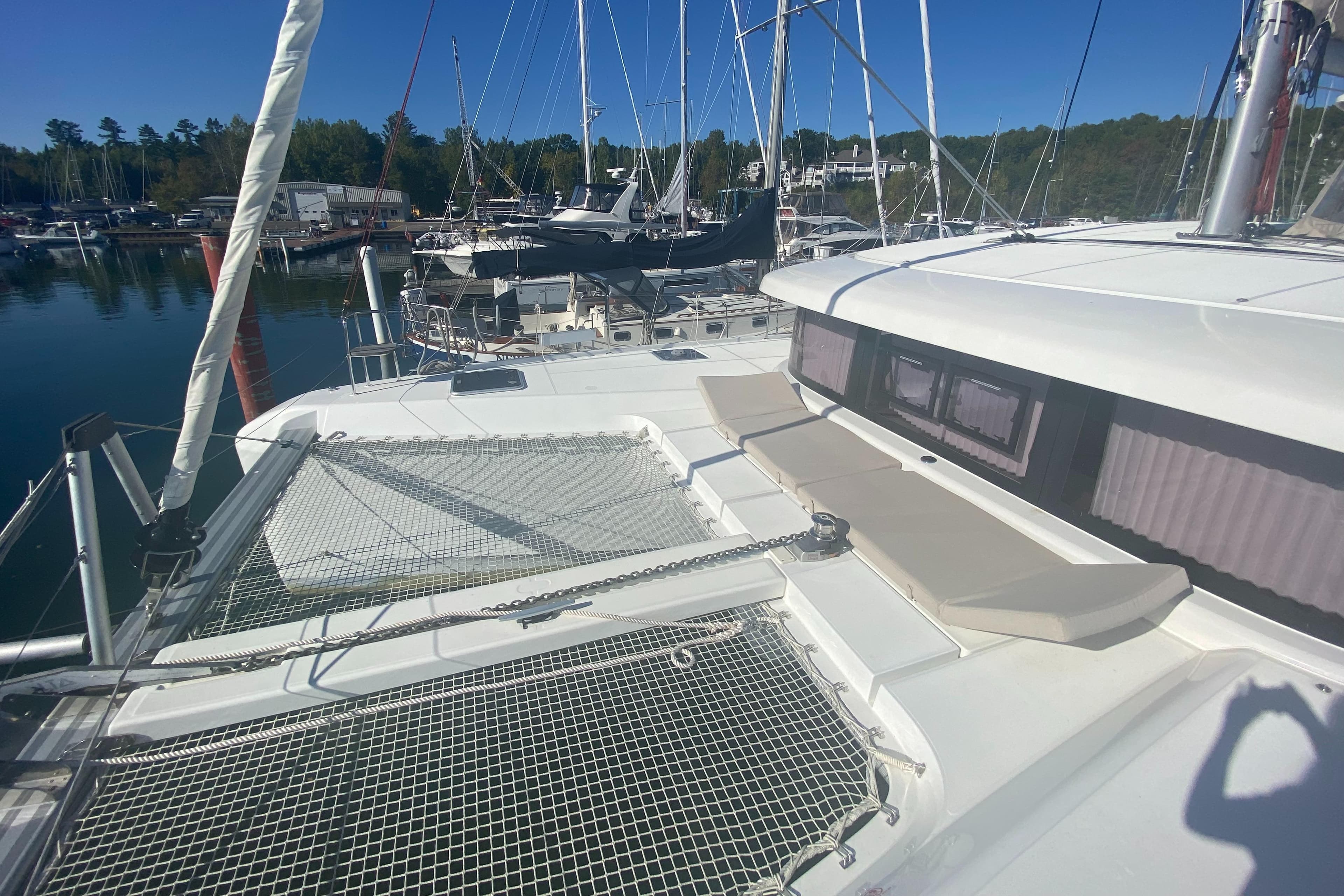 2022 Lagoon 42 catamaran docked in a marina, featuring spacious deck and netting.