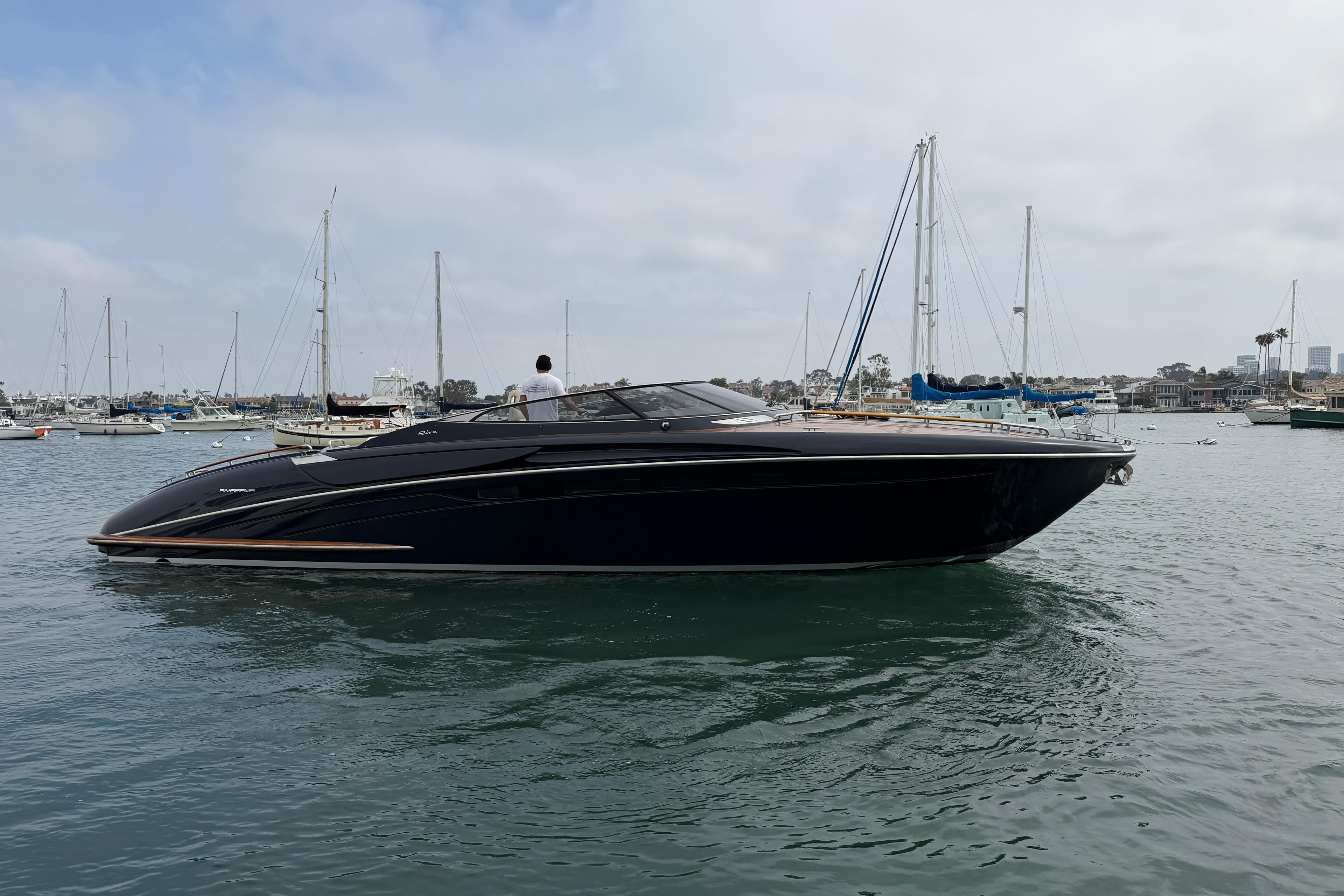 2012 Riva 44' Rivarama luxury yacht cruising in a marina with sailboats.