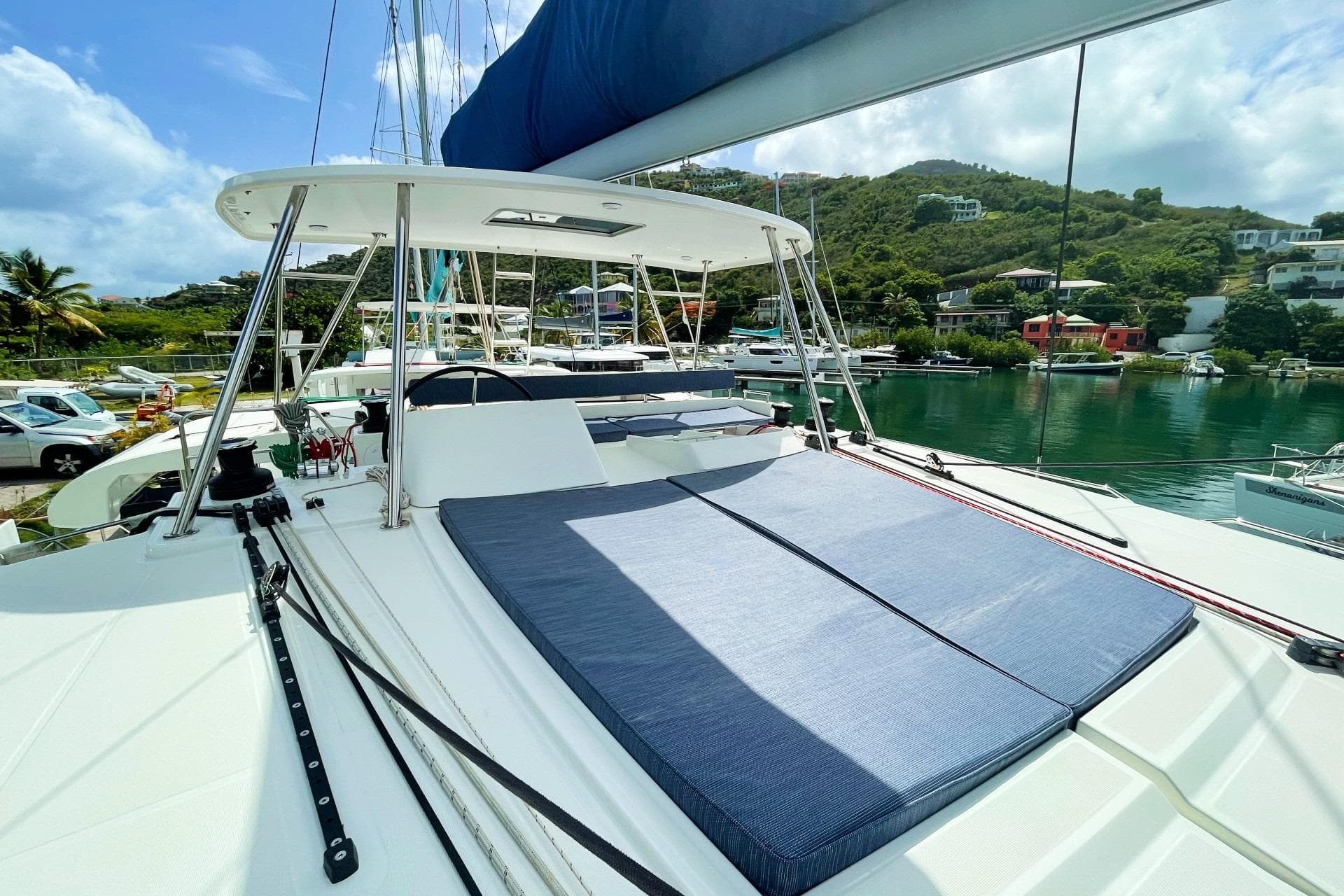 2021 Lagoon 450 F catamaran with sunbathing area, docked in a scenic marina.