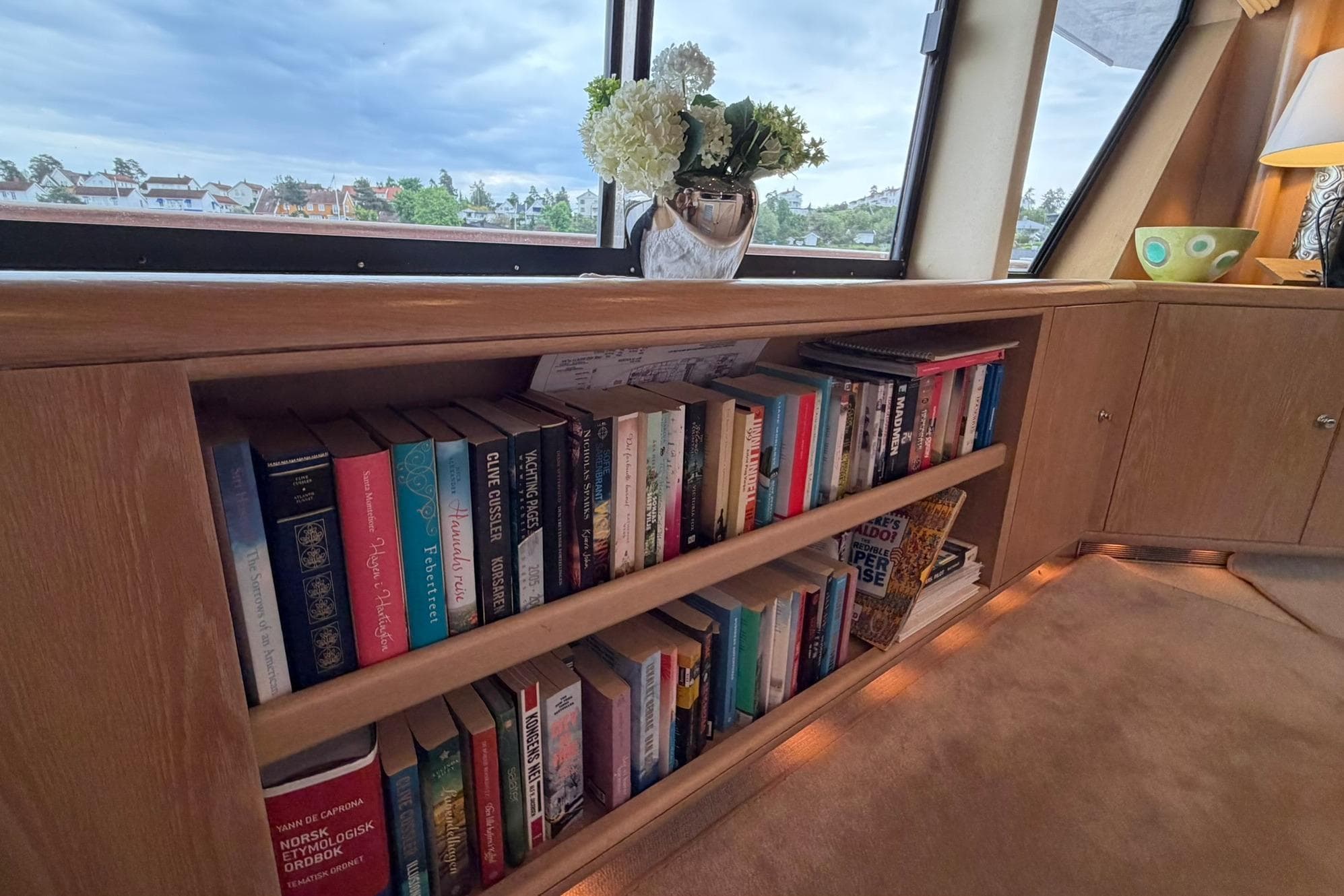 Bookshelf on Lowland Netship 97 yacht, 1990 model, with books and decorative items.